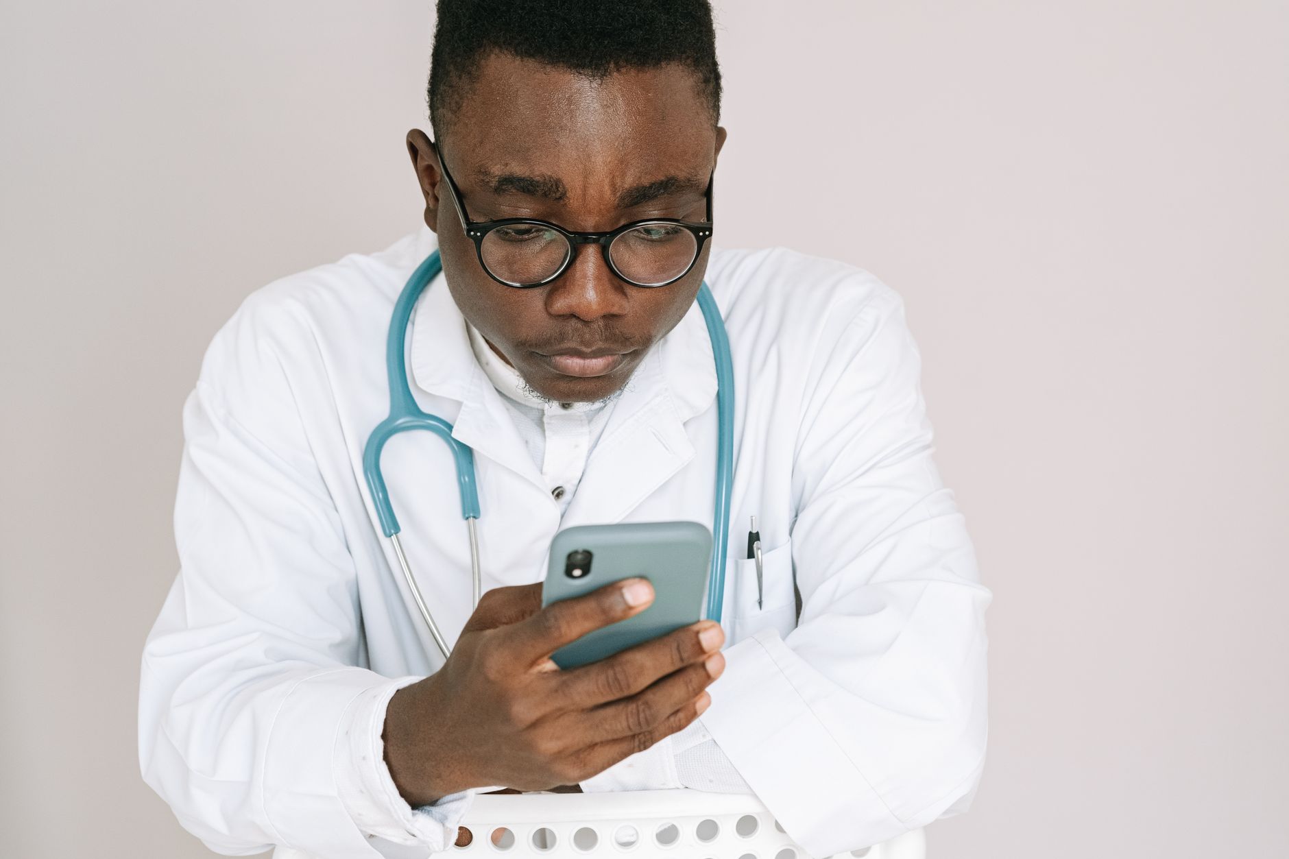 Close-up of a doctor holding a smartphone displaying a multilingual patient portal app.