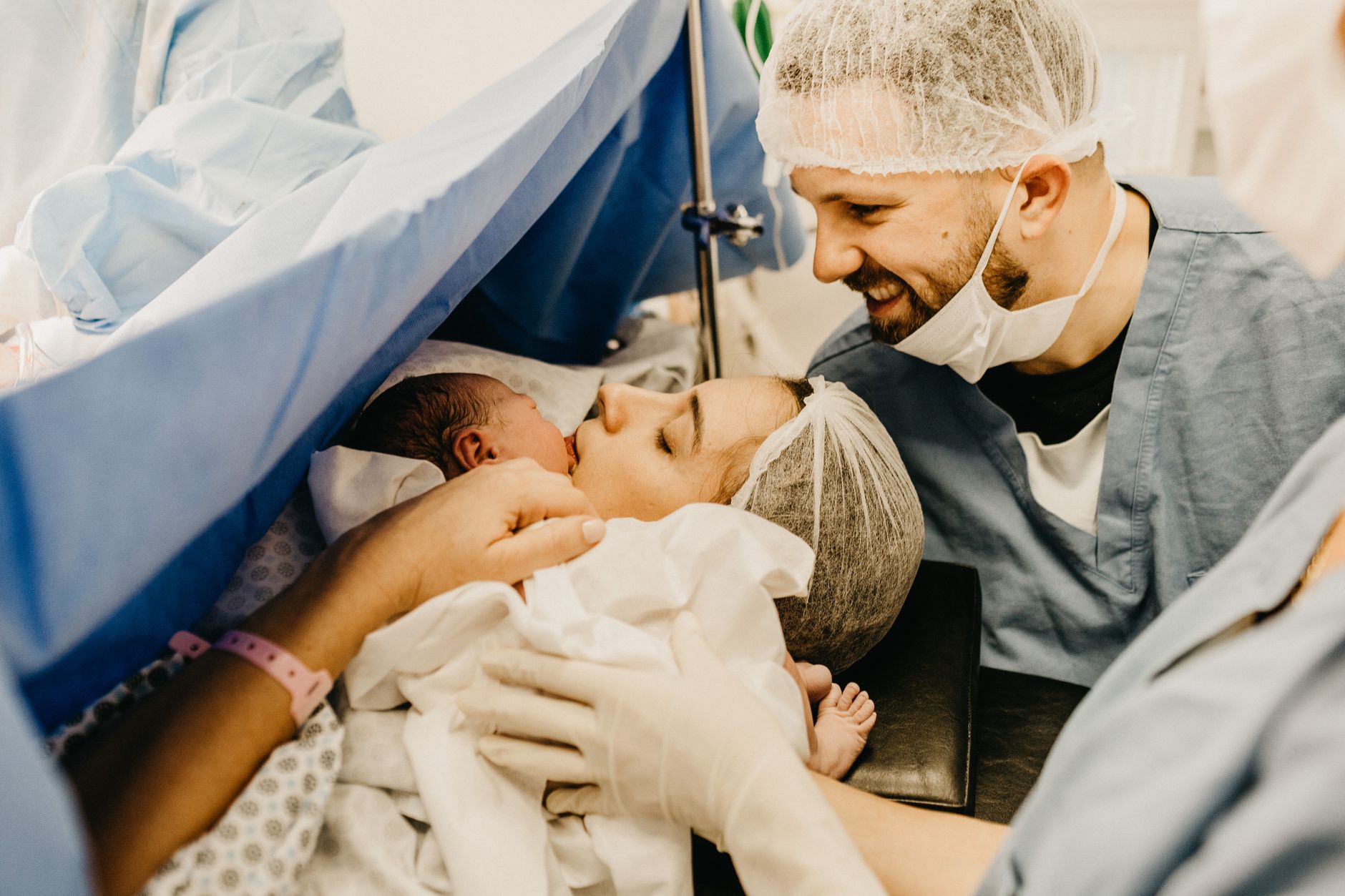 New parents joyfully meet their newborn in a hospital delivery room.