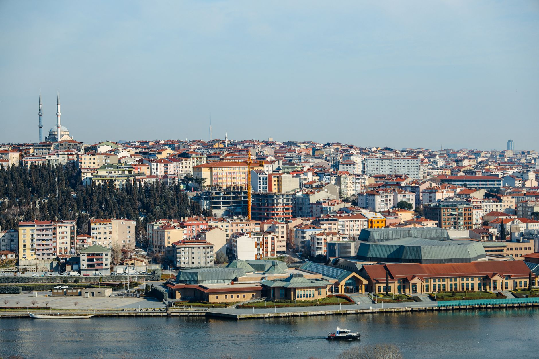 A panoramic view of Istanbul featuring buildings, a river, and mosques under a clear sky.
