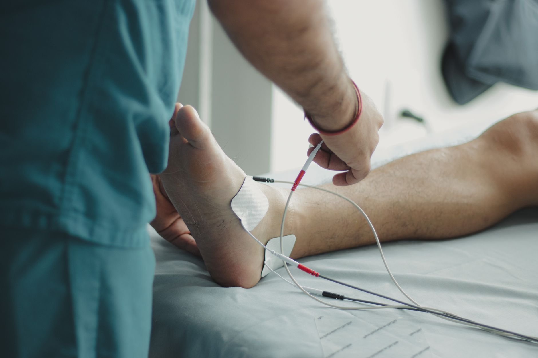 A physiotherapist attaches electrodes to a patient's foot for recovery assessment.