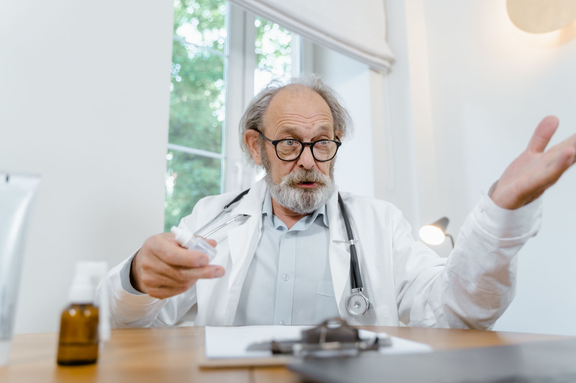 A doctor in a white coat explains a pain management plan, using medication and notes in his office.