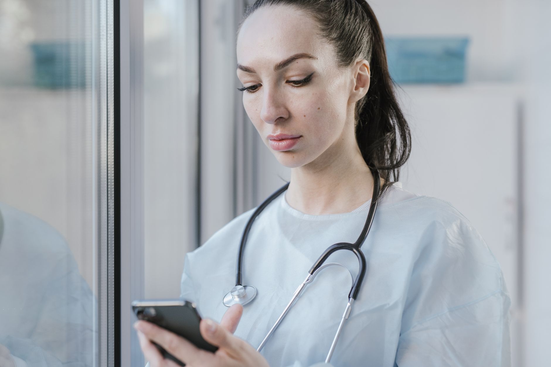 A clinician in a medical setting examines a wound photo on a smartphone.