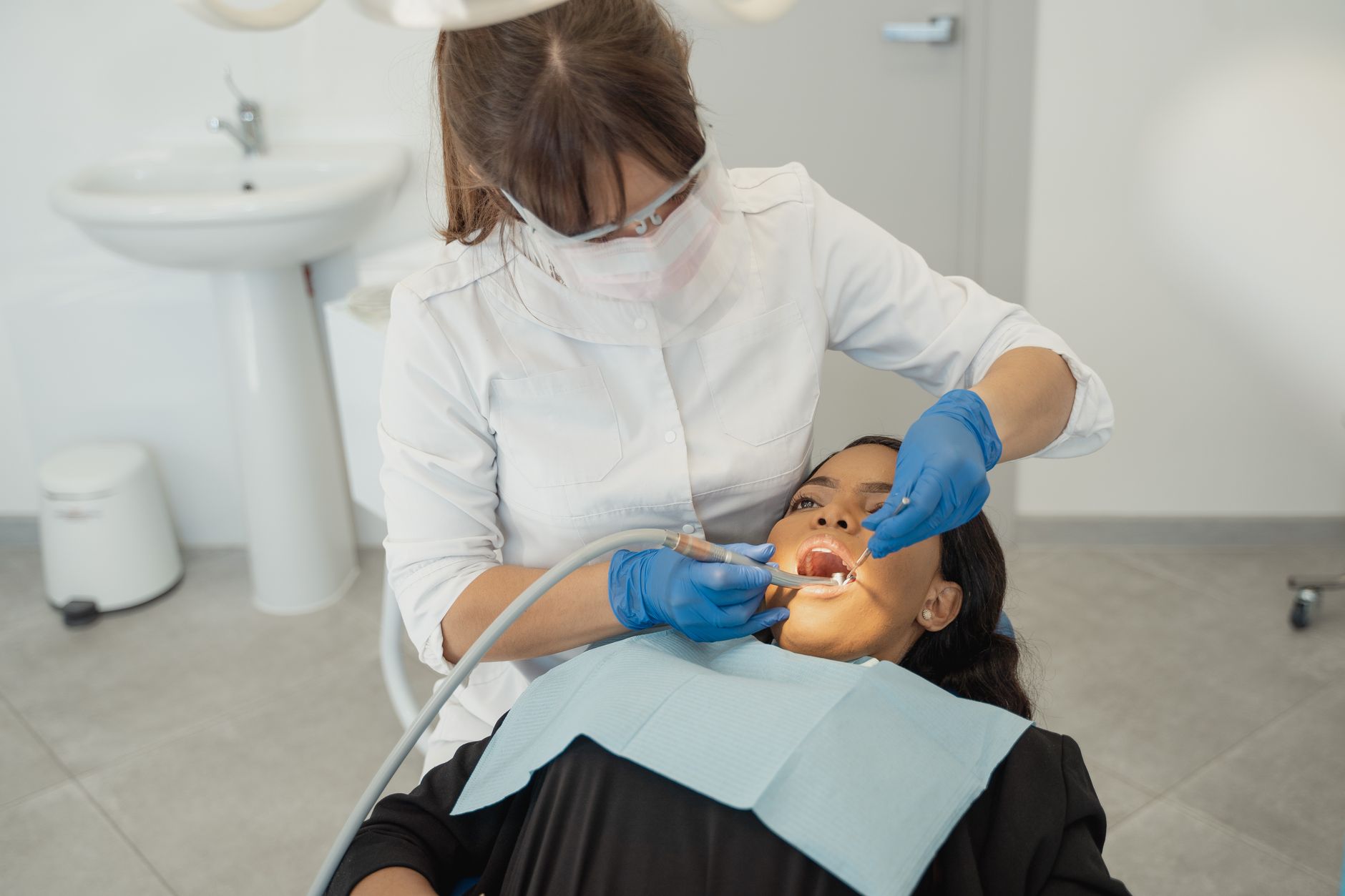 A dentist examines a patient's teeth in a Turkish clinic, preparing for dental surgery.