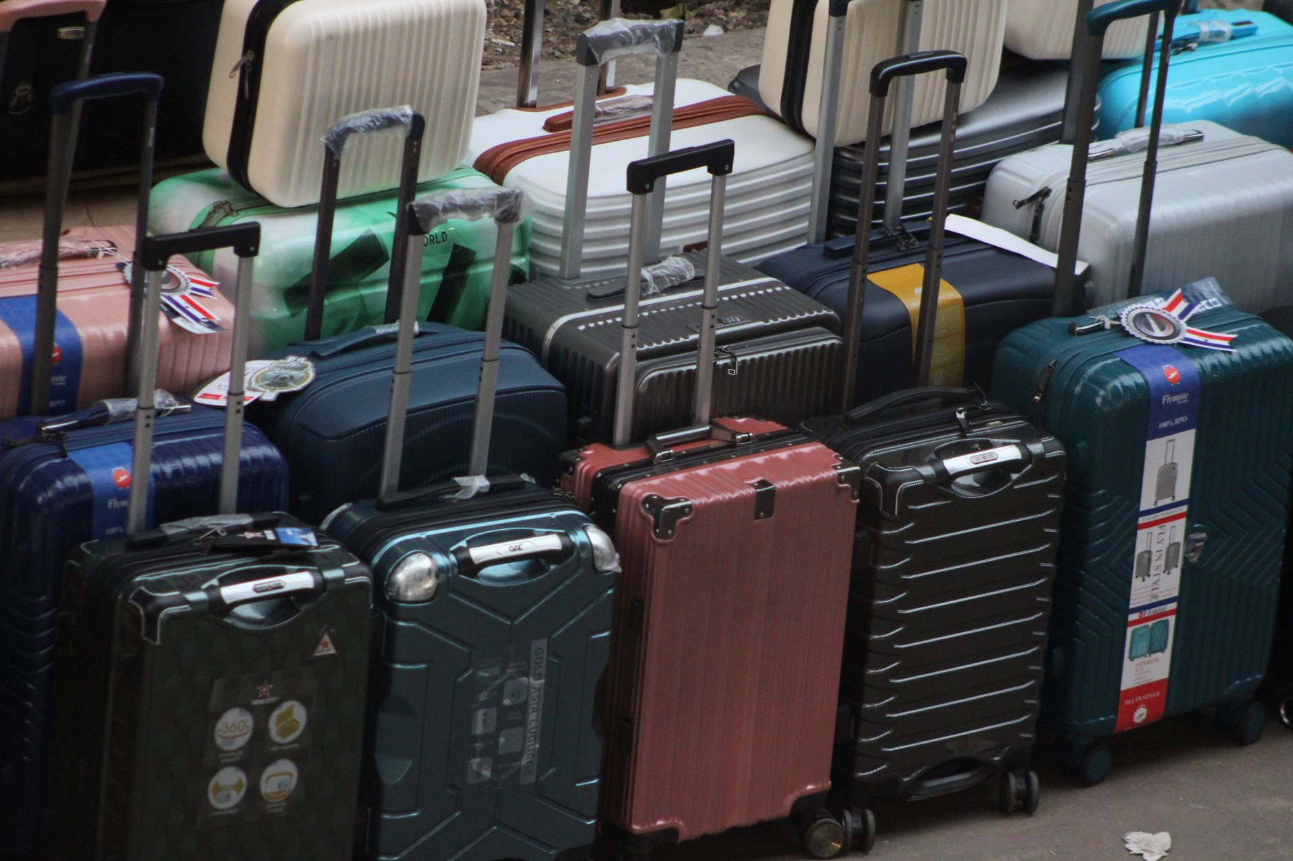 Various colorful suitcases and luggage stacked at a market featuring different styles.