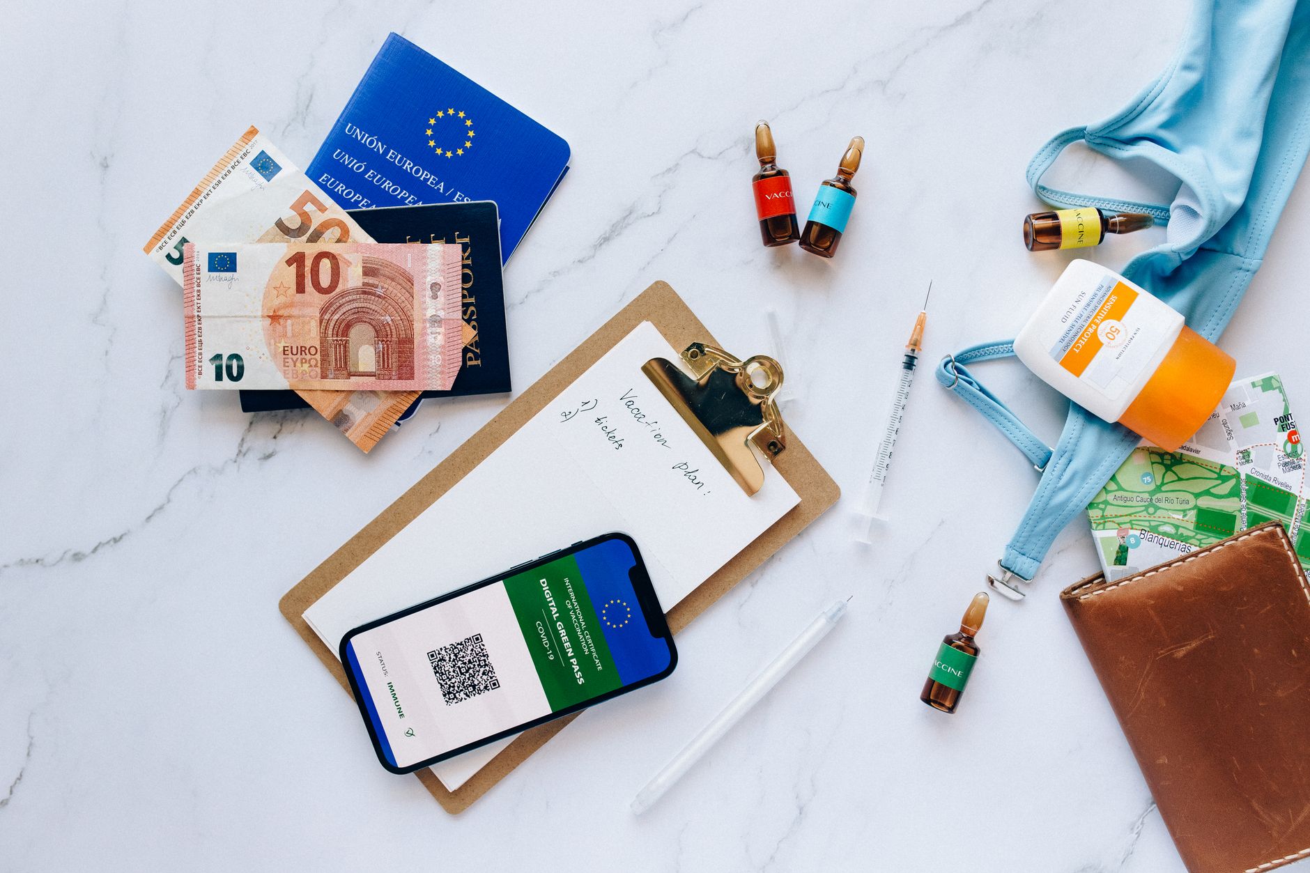 Close-up of a passport, vaccination details, and Euro currency on a desk.