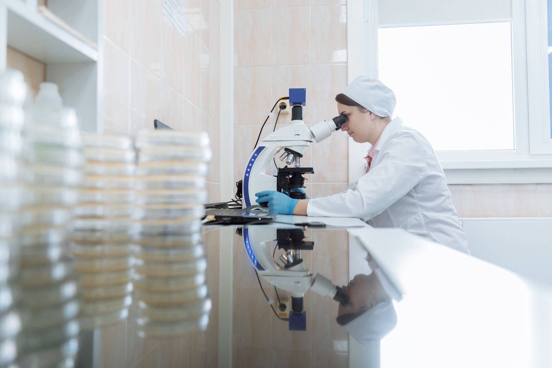 Scientist analyzing samples under a microscope in a lab setting.