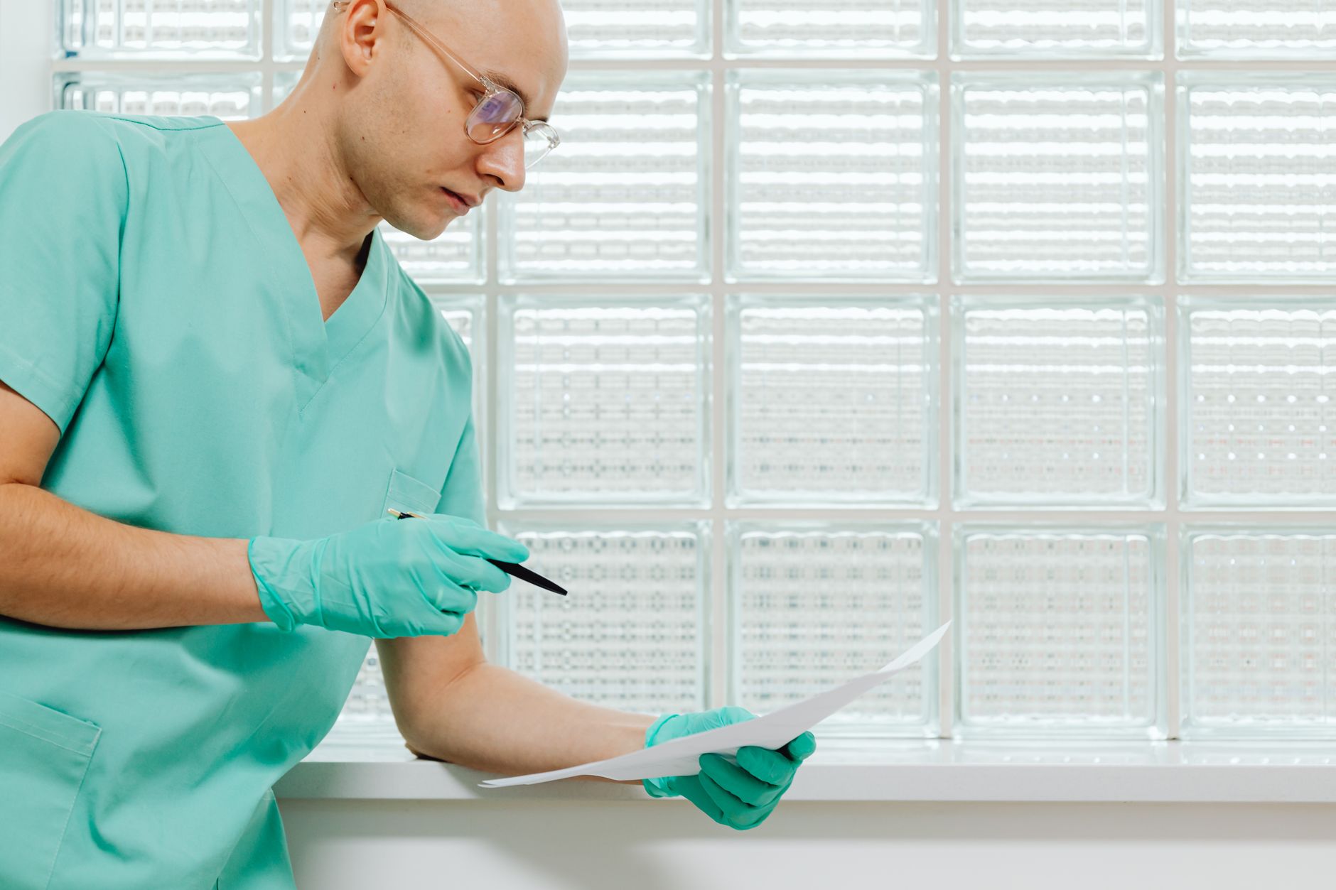 A healthcare worker in scrubs analyzes paperwork in a bright clinic.