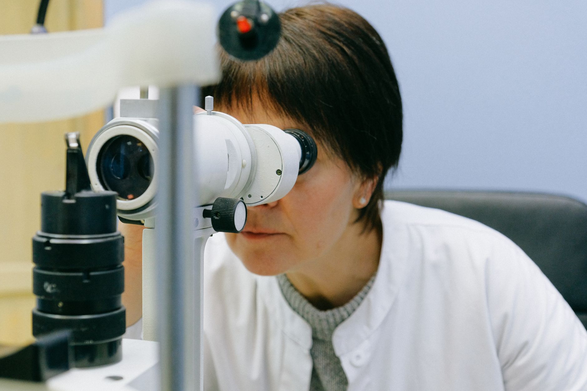 A practitioner examines a patient through an eye diagnostic device at an eye clinic.