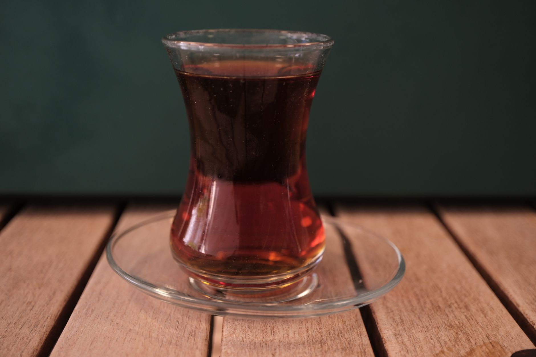 نمای نزدیک از یک لیوان گل‌نرگسی پر از چای ترکی روی نعلبکی.