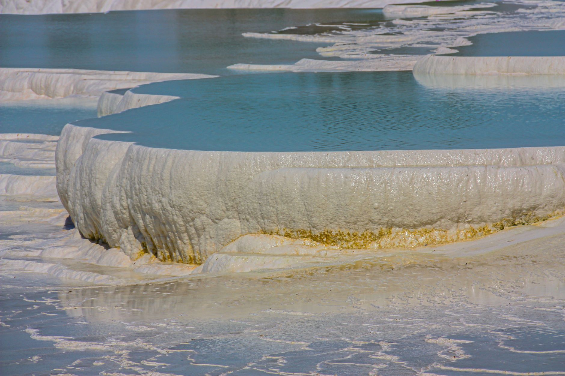 Close-up view of thermal springs in Yalova, showcasing layered white travertine formations and tranquil blue waters.