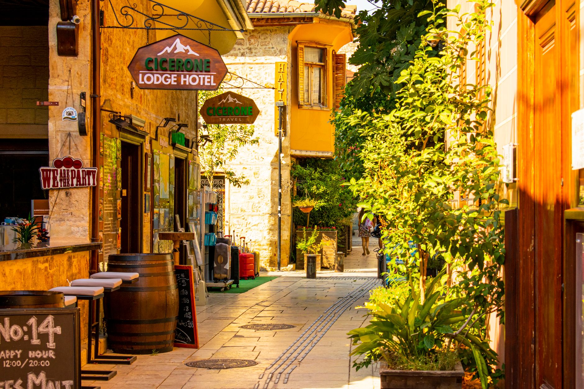 زقاق خلاب في أنطاليا يضم فندق Cicerone Lodge ومساحات خضراء نابضة بالحياة.