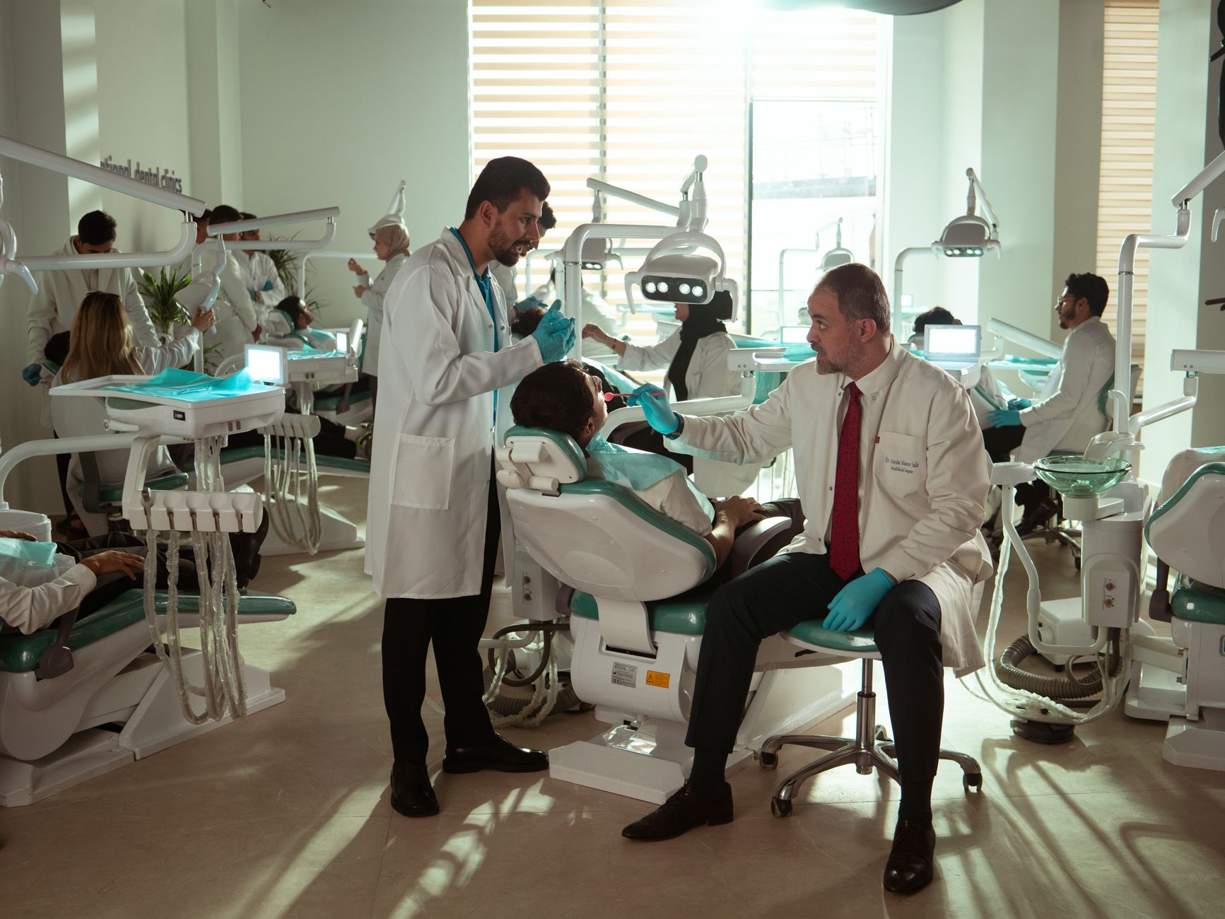A modern dental clinic featuring multiple dental professionals attending to patients in a bright, welcoming environment.
