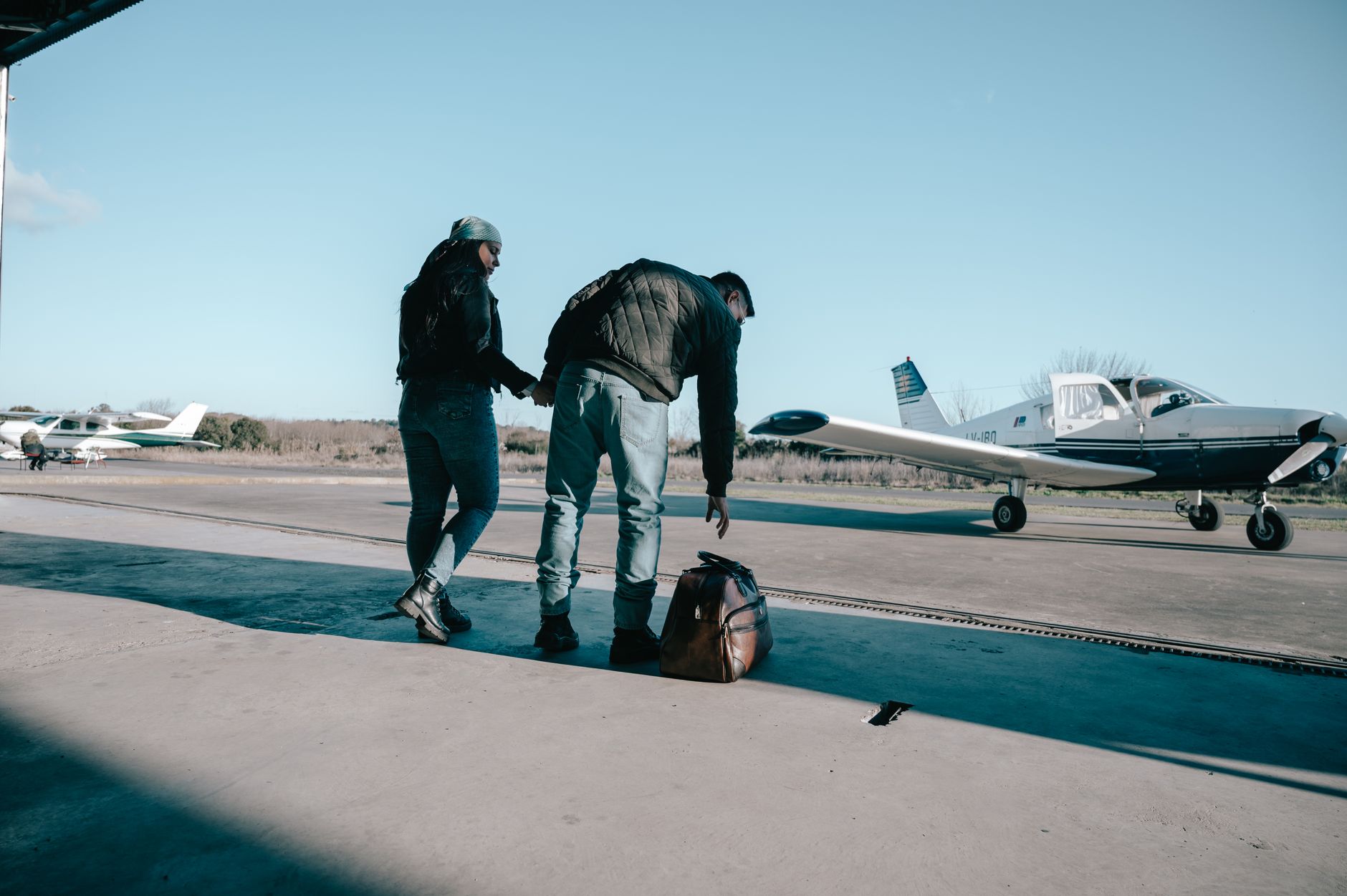A couple holding hands at an airfield, preparing to board a small plane for their journey to Türkiye.