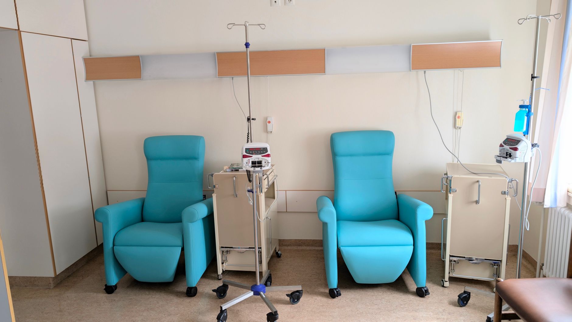 Welcoming interior of a Turkish hospital featuring two turquoise chairs and medical equipment.