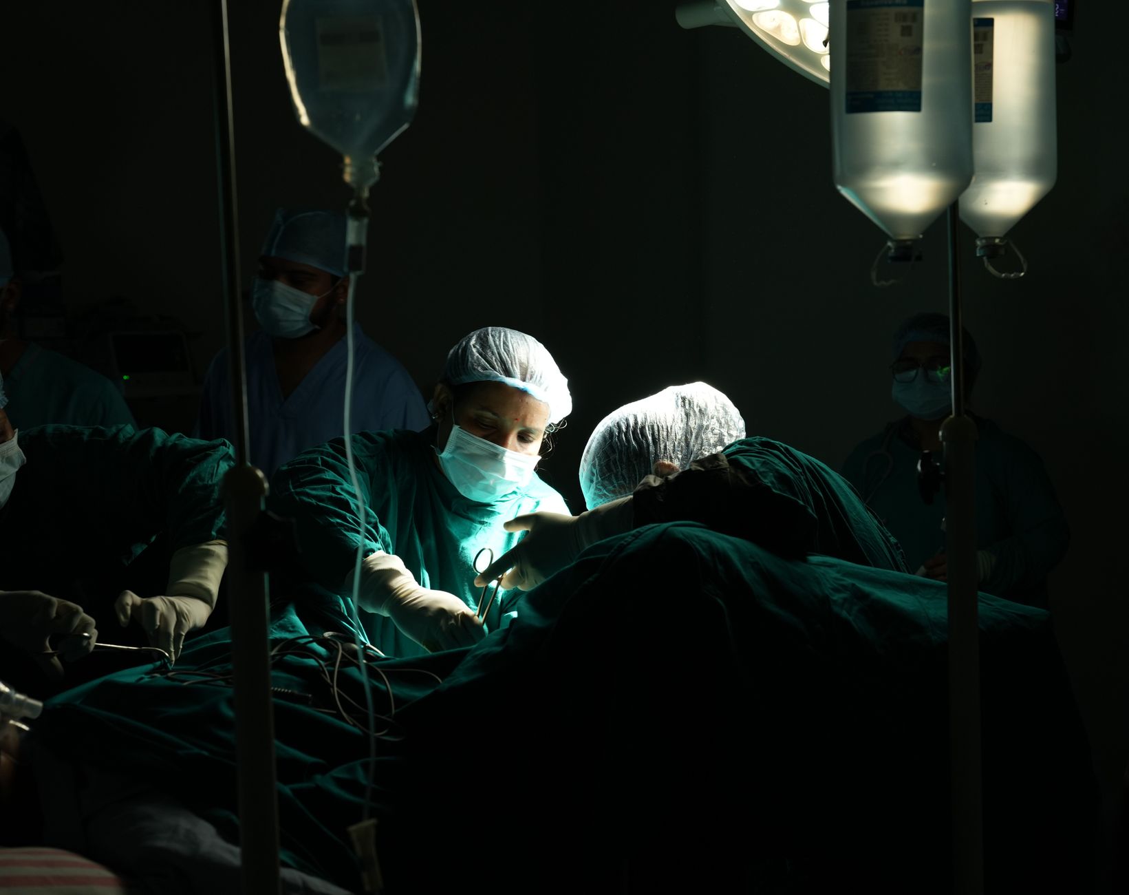 Doctors and nurses perform surgery under dim lighting in a Turkish hospital.