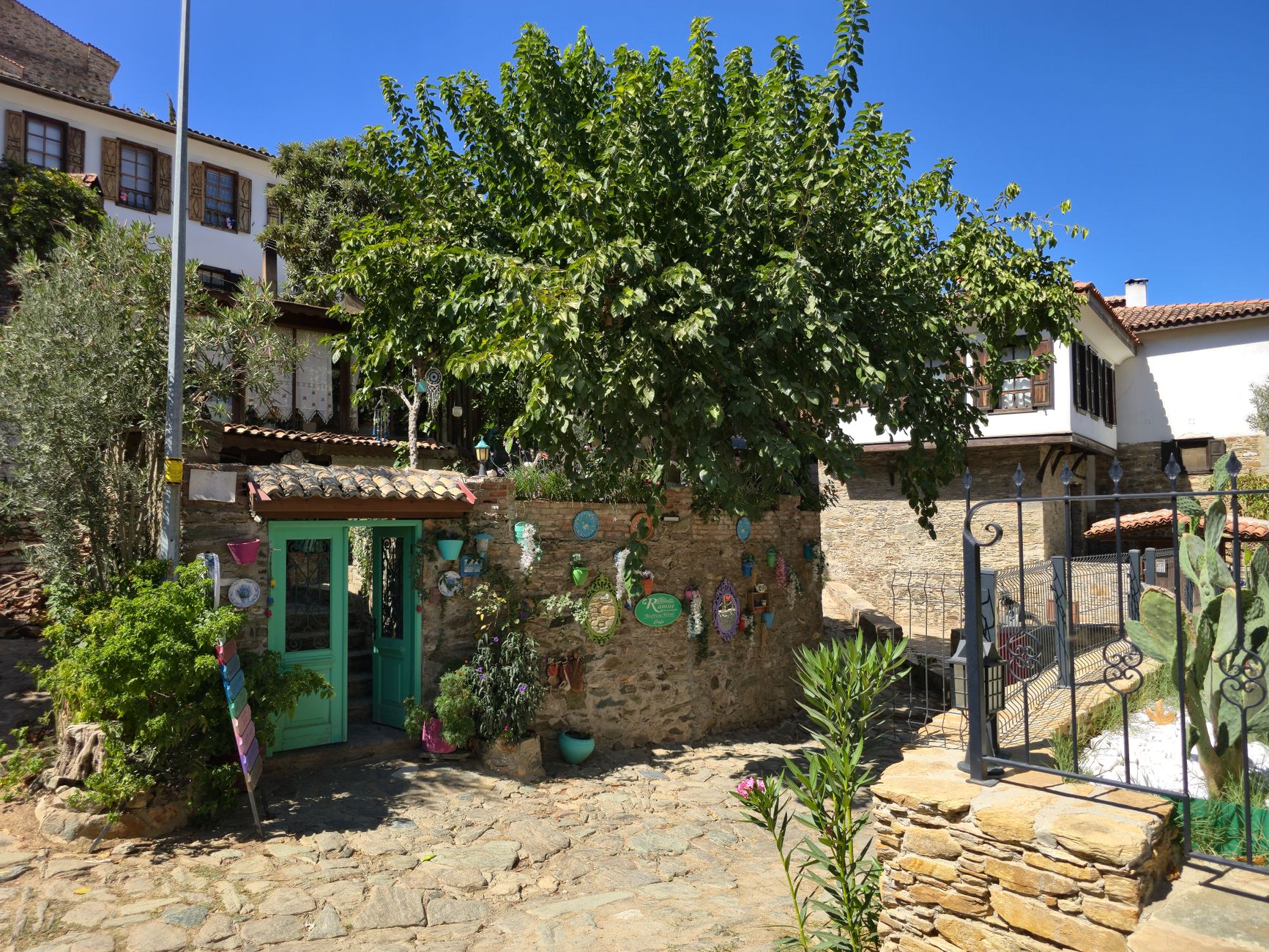 نمایی دیدنی از خانه‌های سنتی در روستای شیرینده، با تزئینات پرجنب‌وجوش و درختی سرسبز.