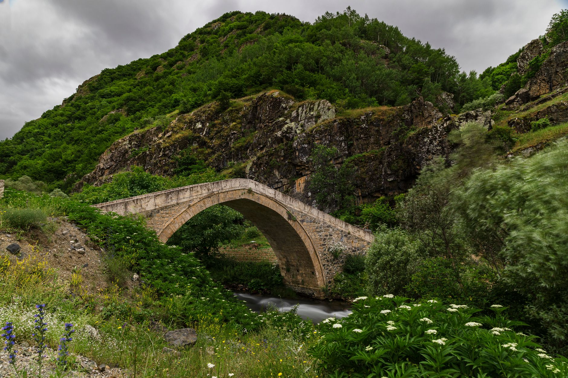 یک پل سنگی طاق‌دار از دوره روم بر روی آب آرام در استپ آناتولی، احاطه شده با سرسبزی.
