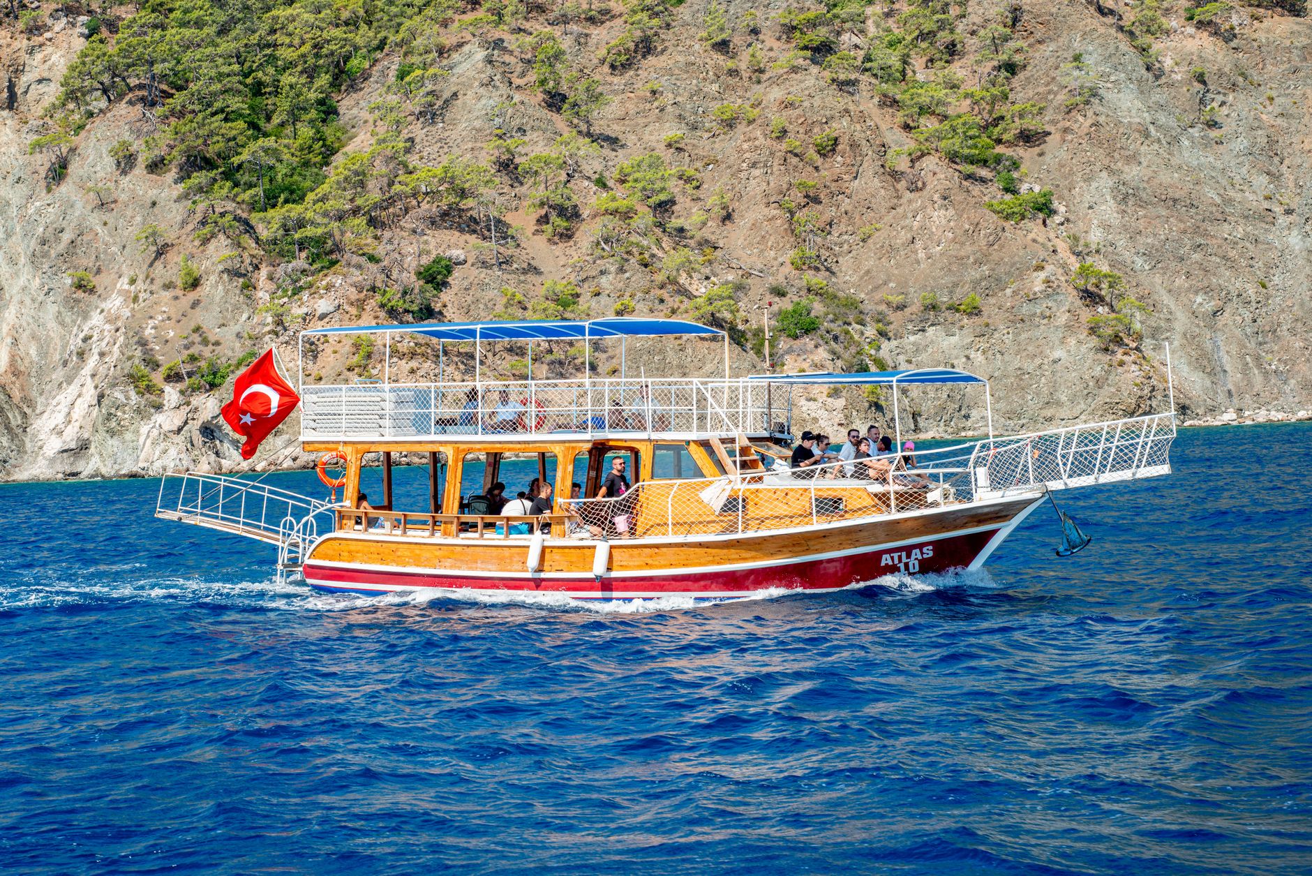 A traditional wooden boat with Turkish flag sailing in blue waters near Kaş, perfect for snorkeling trips.