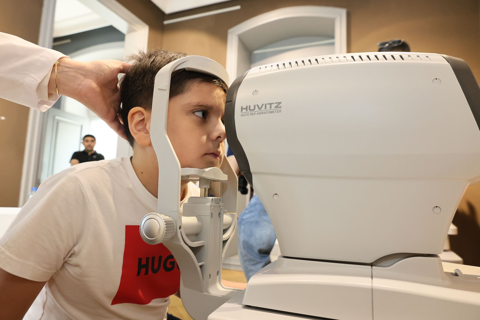 A child having an eye examination using a Huvitz auto refractometer.