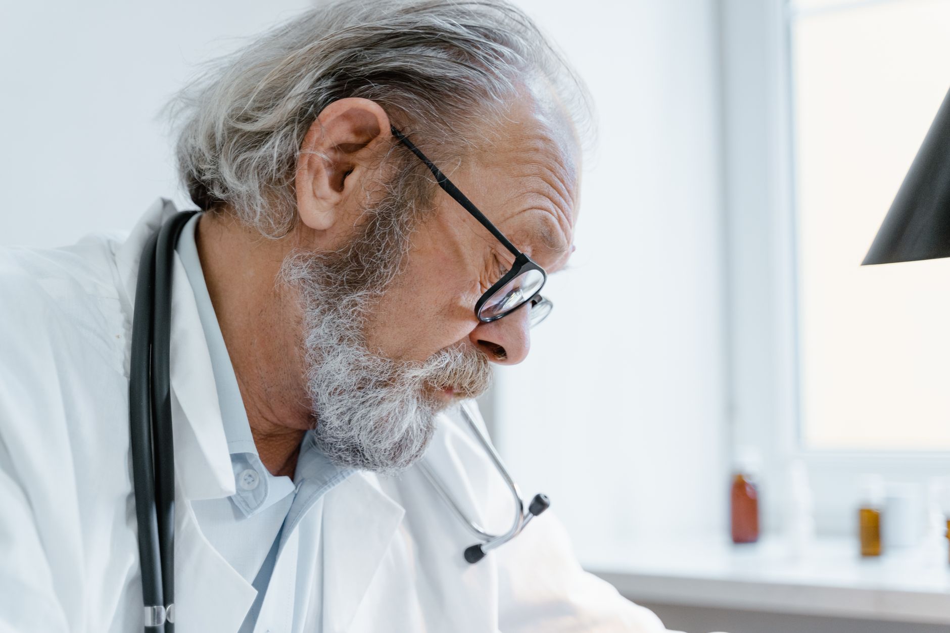 Close-up of an elderly doctor with glasses, focused on a patient consultation.