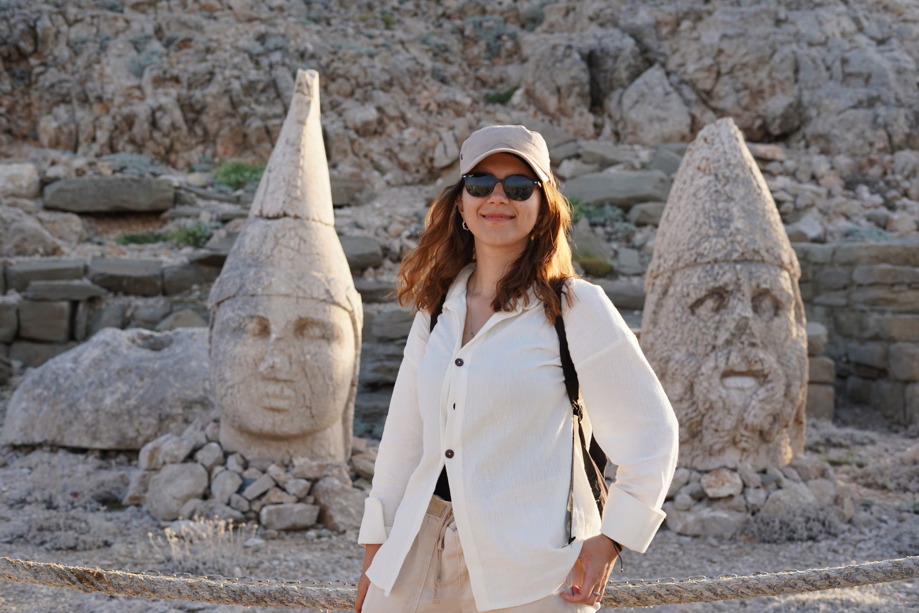 Bir kadın Nemrut Dağı'ndaki antik devasa heykellerin önünde poz veriyor.