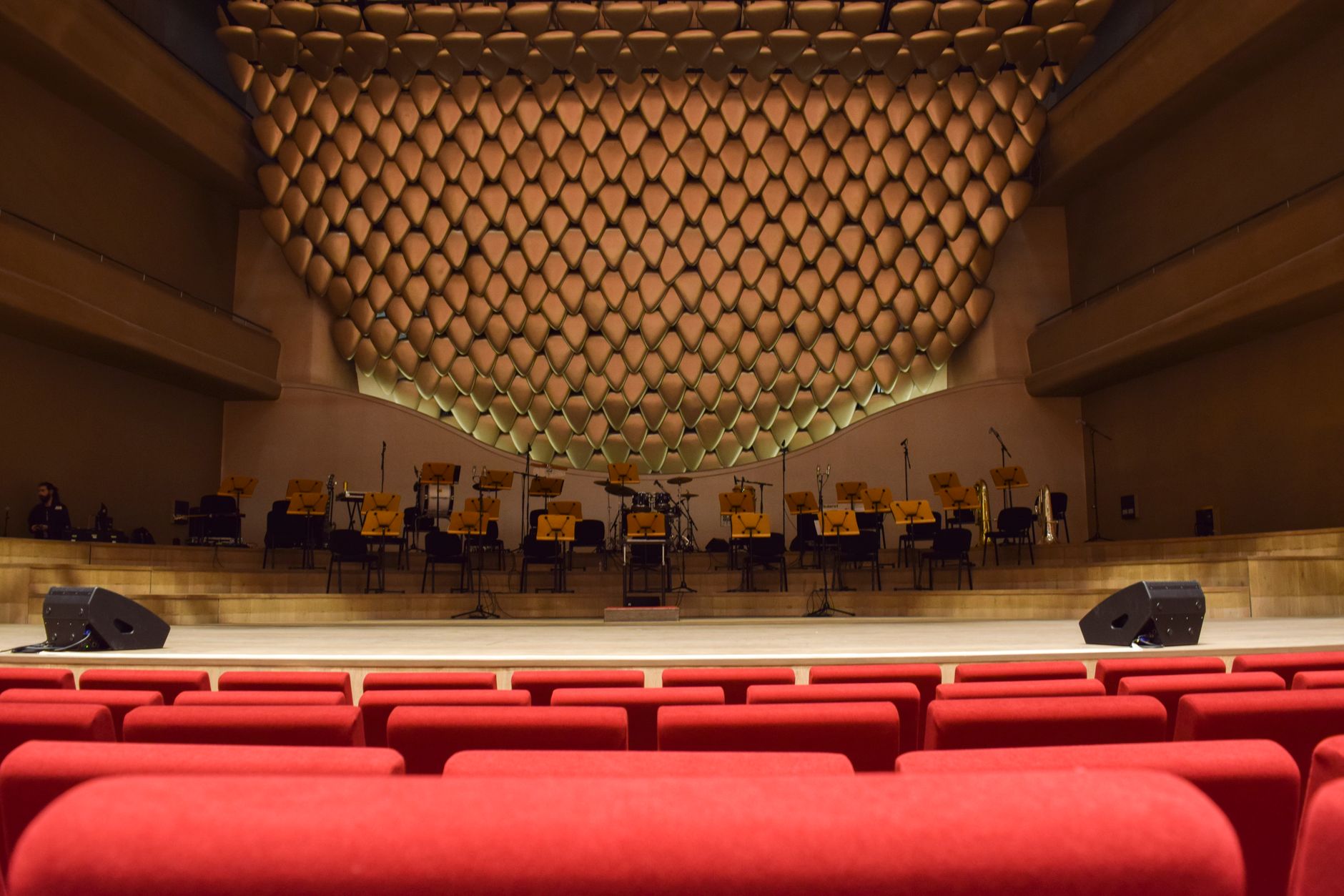 Ankara'da kırmızı koltukları ve klasik bir performans için hazırlanmış sahnesi olan modern bir konser salonunun iç görünümü.