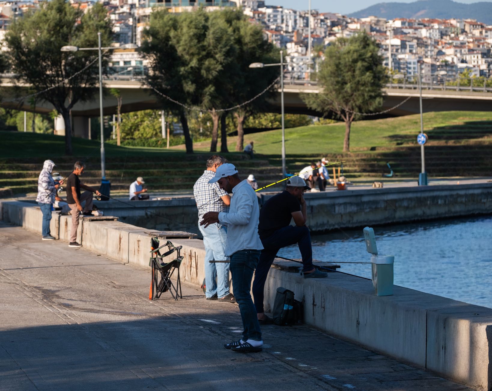 Sonbaharda İzmir Kültürpark'ta su kenarında balık tutan insanlar.