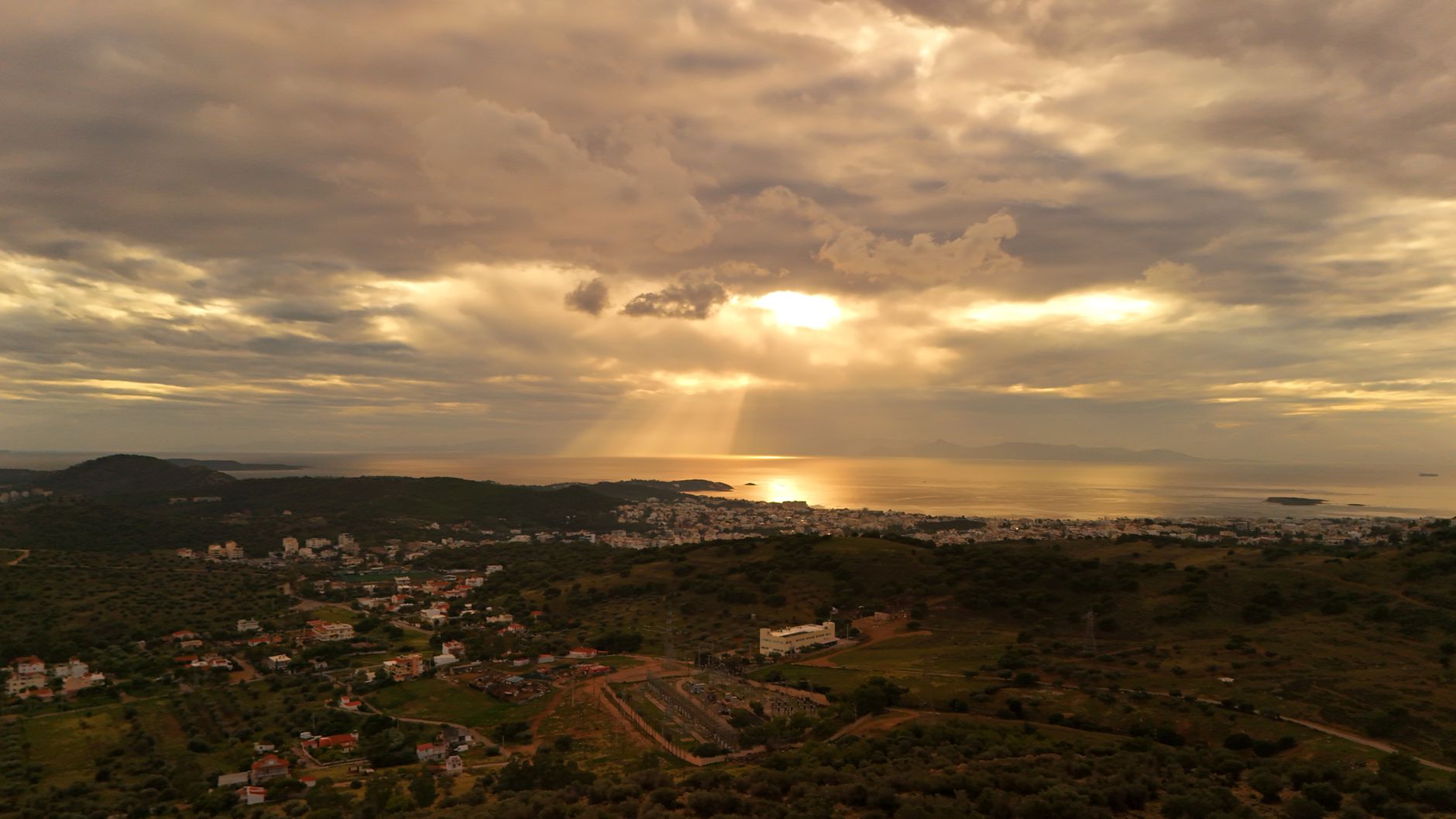 View of Ayvalık with olive groves and the Aegean Sea at sunset, showcasing serene clouds.