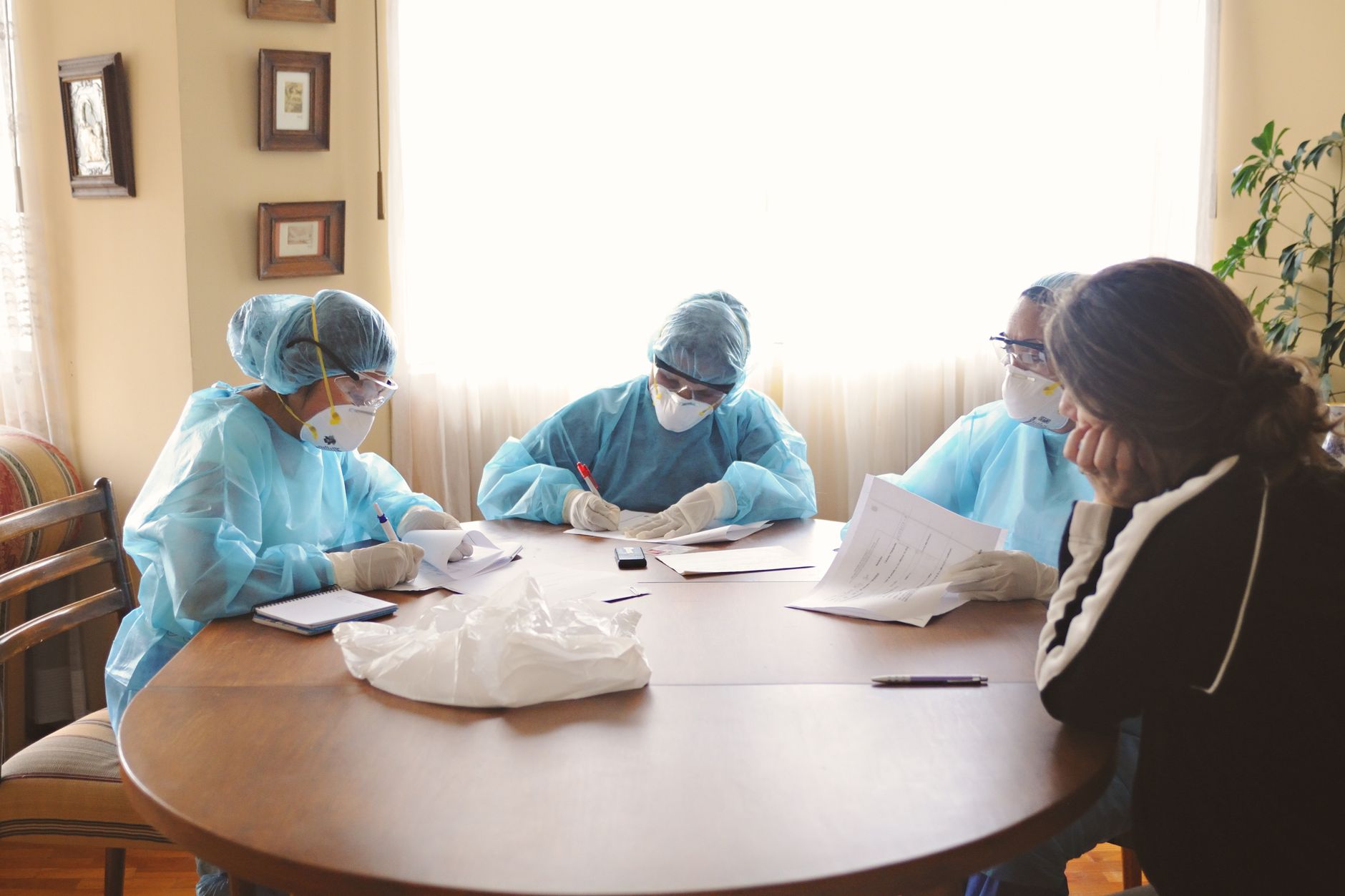 A group of healthcare professionals in protective gear discussing documents at a table.