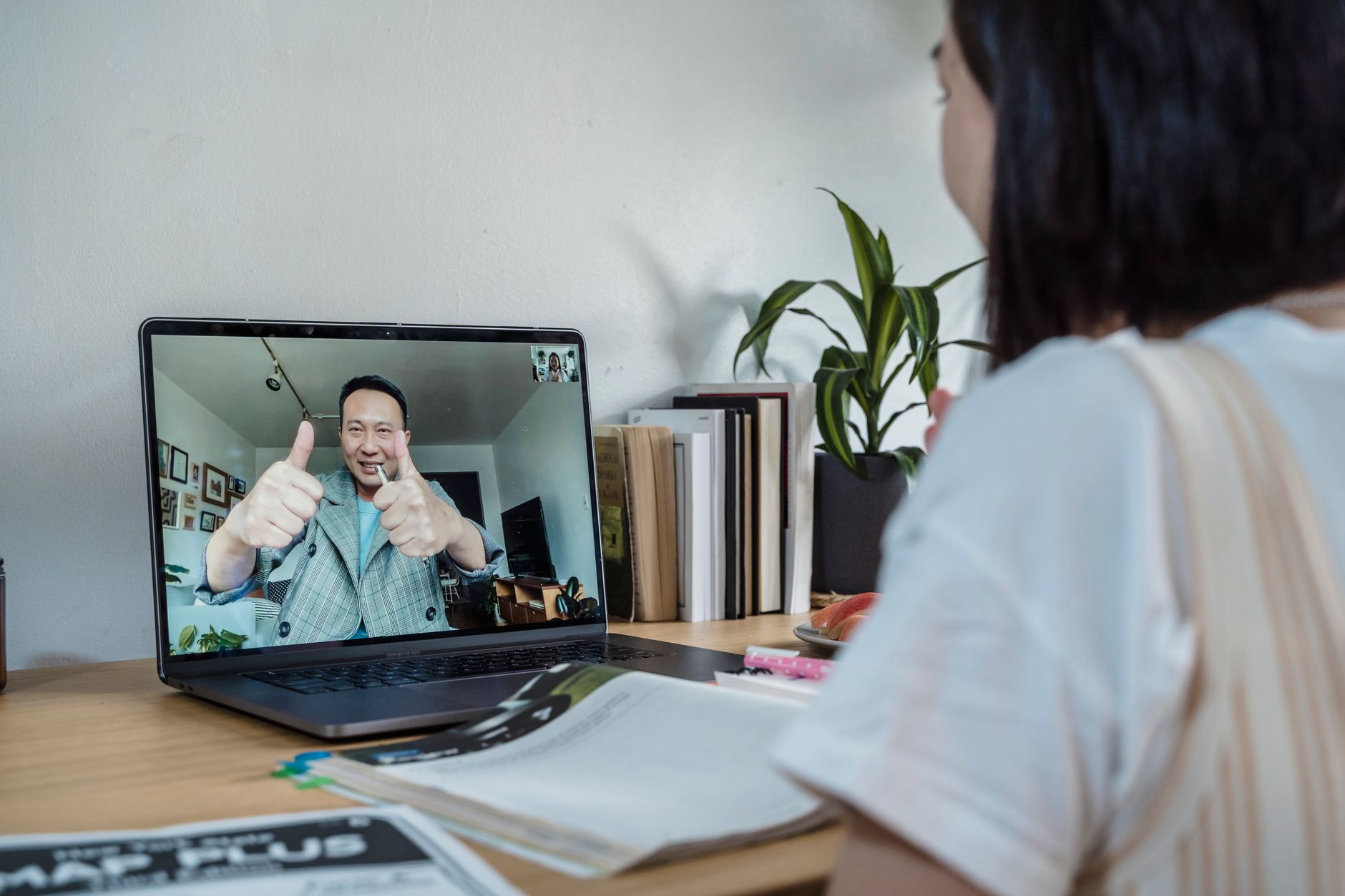 A dietitian giving a thumbs-up during a virtual coaching session on a laptop.