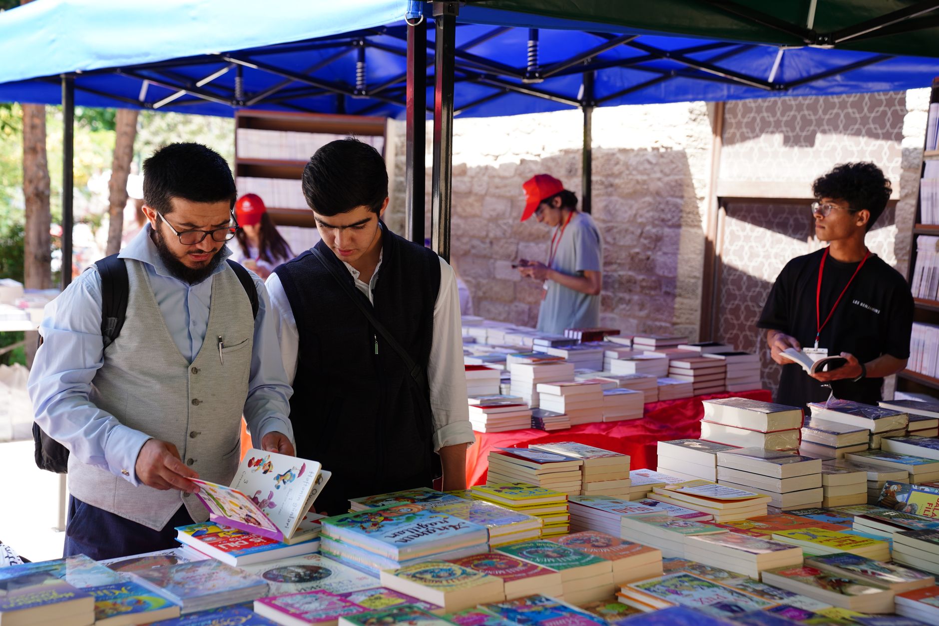دو مرد در حال ورق زدن انواع کتاب‌ها در یک جشنواره فضای باز در ترکیه.