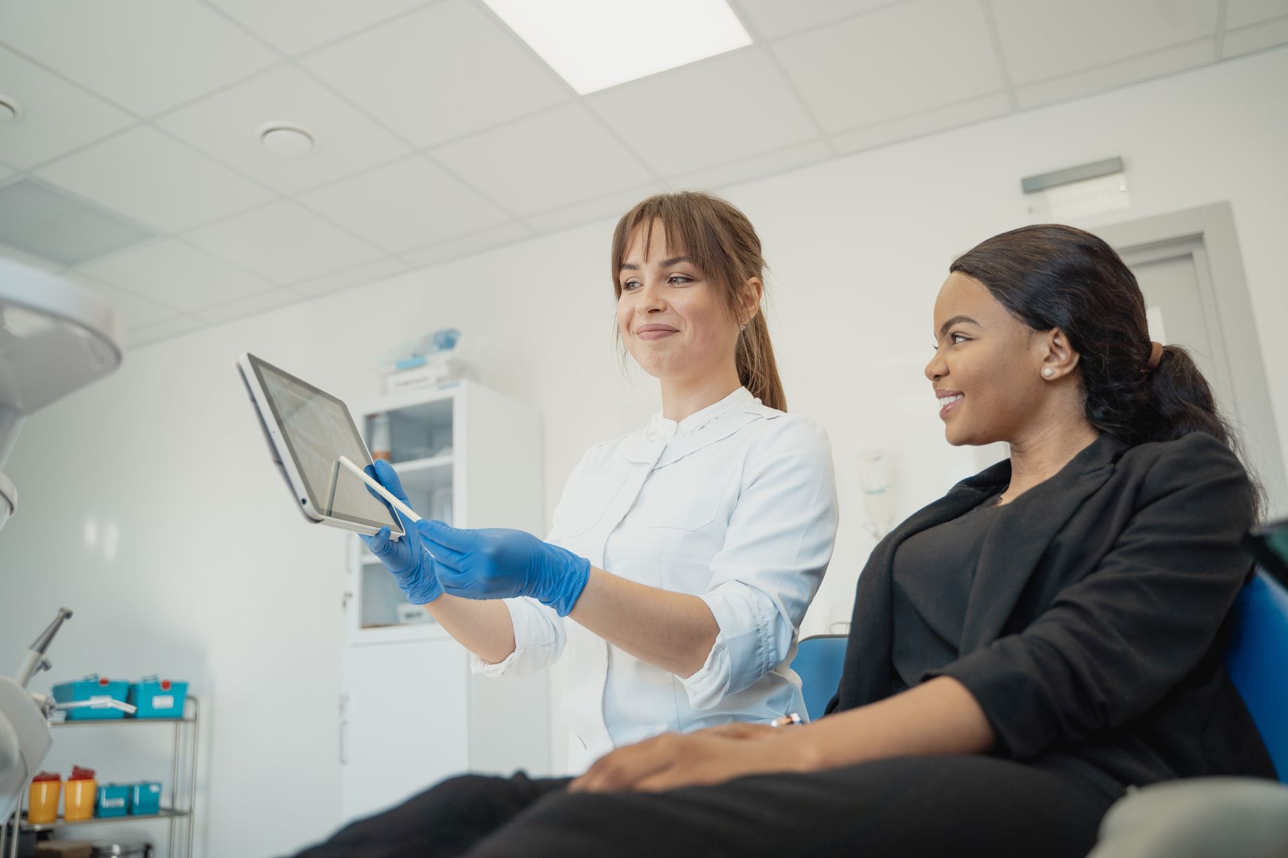 A dentist shows a digital smile design simulation to a patient in a modern dental office.
