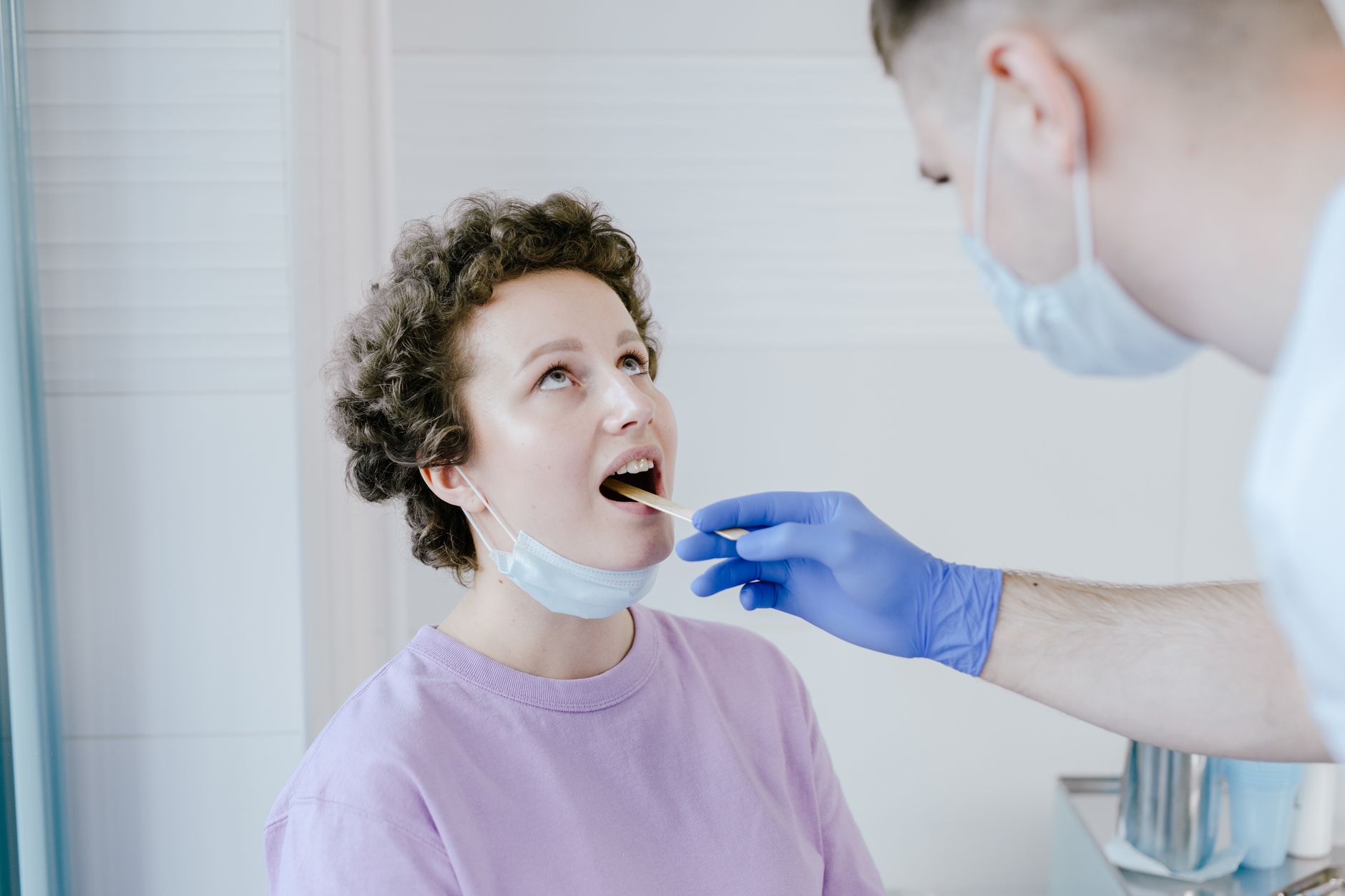 A healthcare professional checks a patient's throat during an examination in a bright clinic.