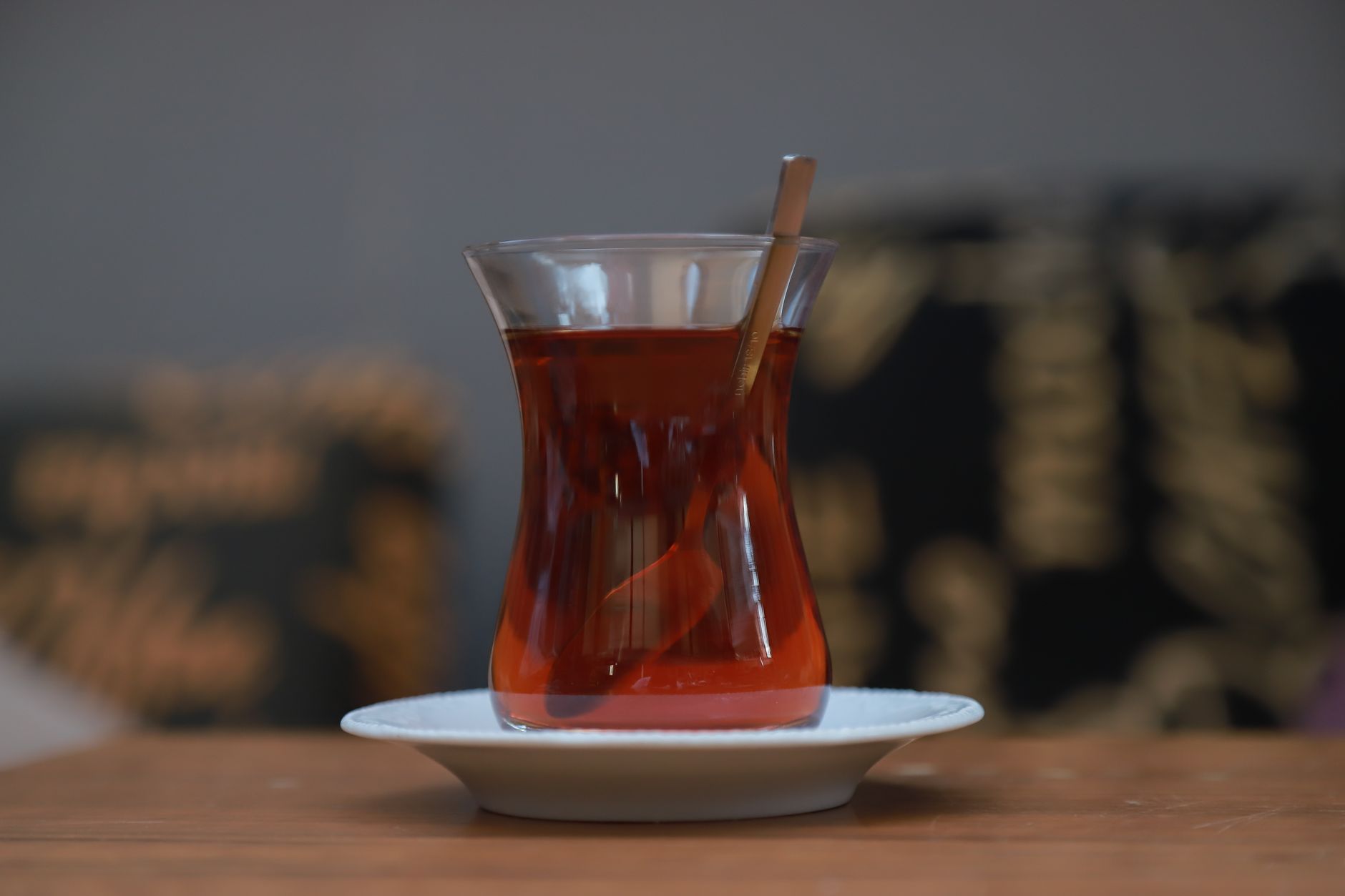 A glass of Turkish tea with a spoon, resting on a plate, symbolizing hospitality.