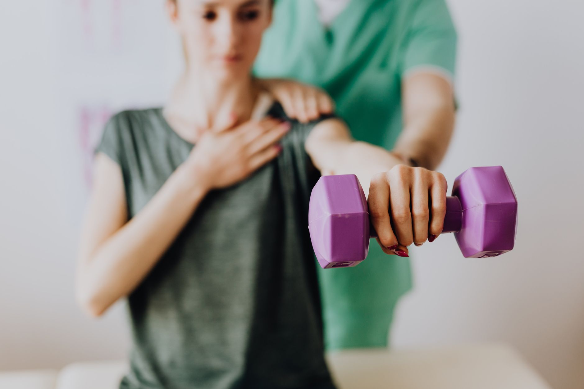 A patient exercises with a purple dumbbell in a Turkish rehabilitation clinic.