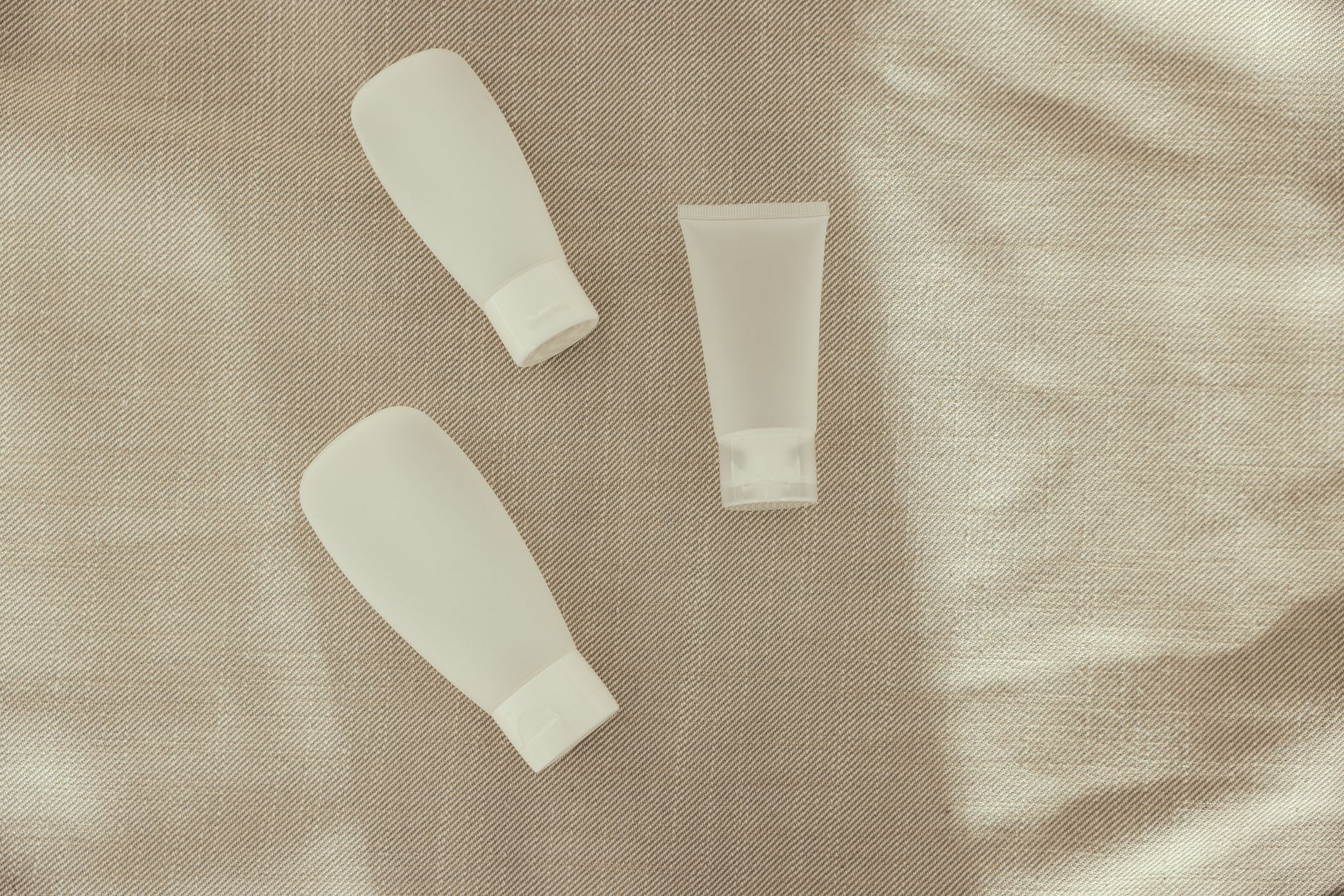 Neatly arranged skincare products including cleanser and moisturizer on a fabric background.