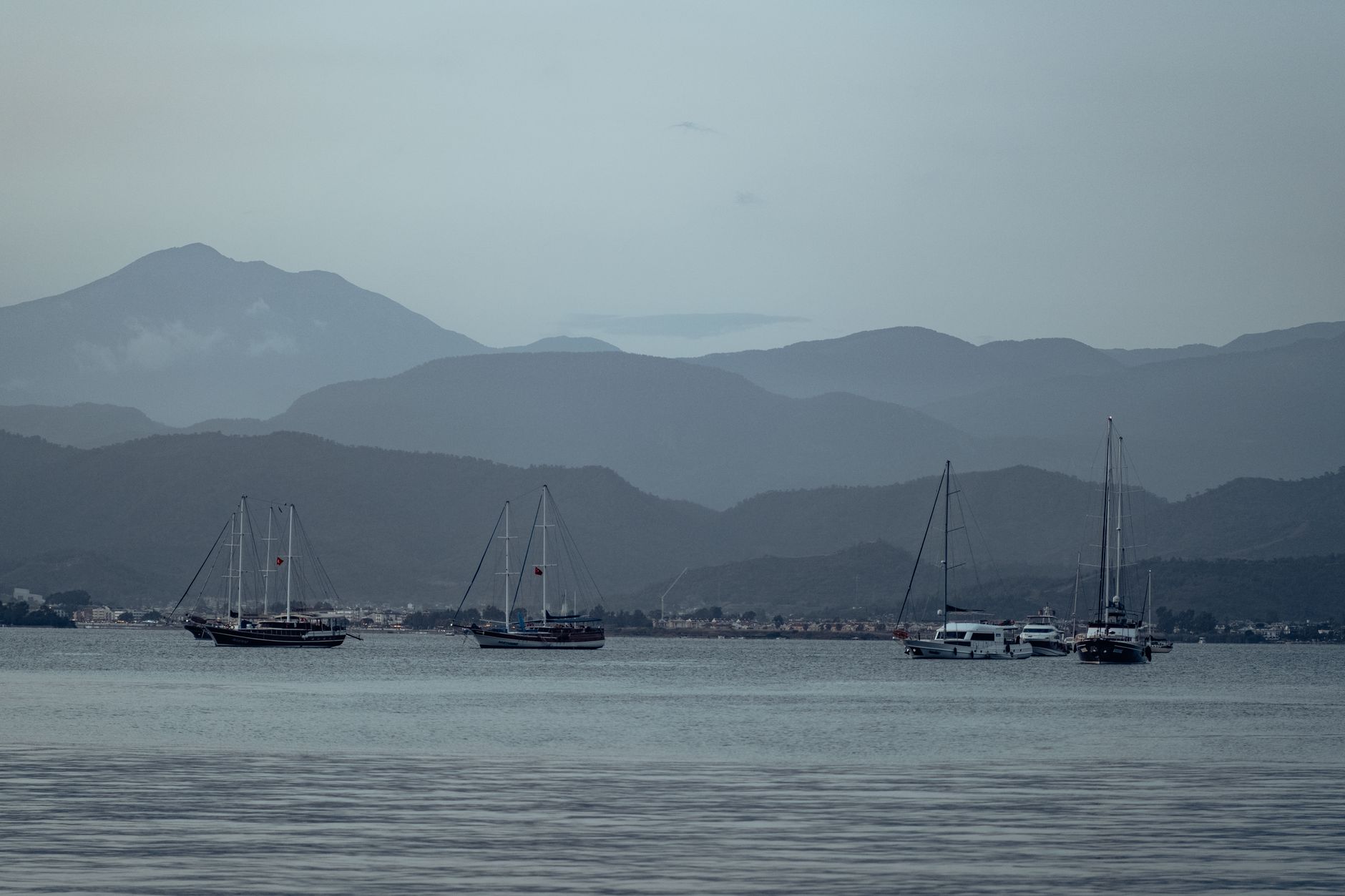 Fethiye limanında dağlarla çevrili geleneksel ahşap guletler demirlemiş hâlde.