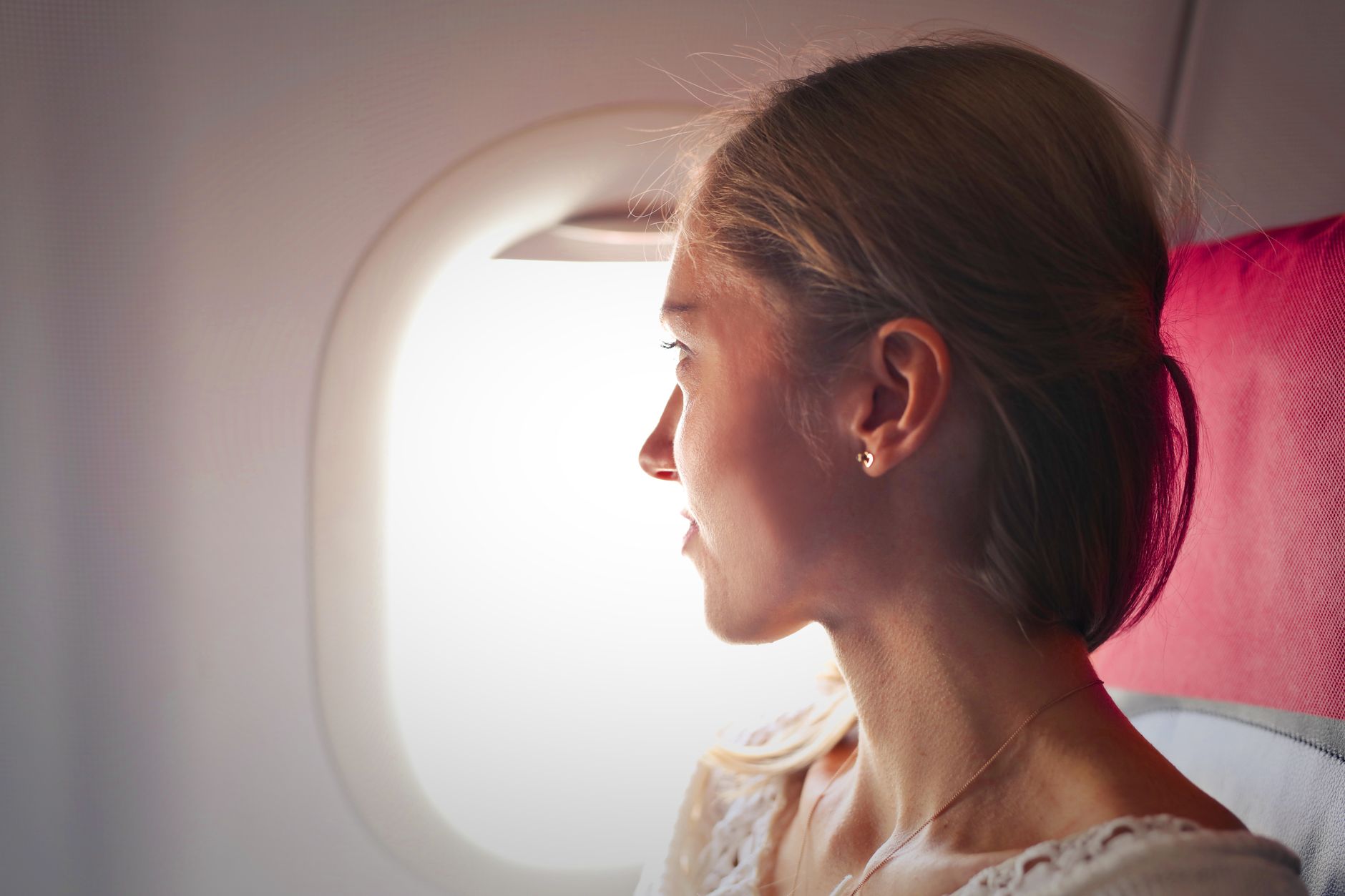 A serene passenger gazes out of an airplane window, reflecting on their journey.