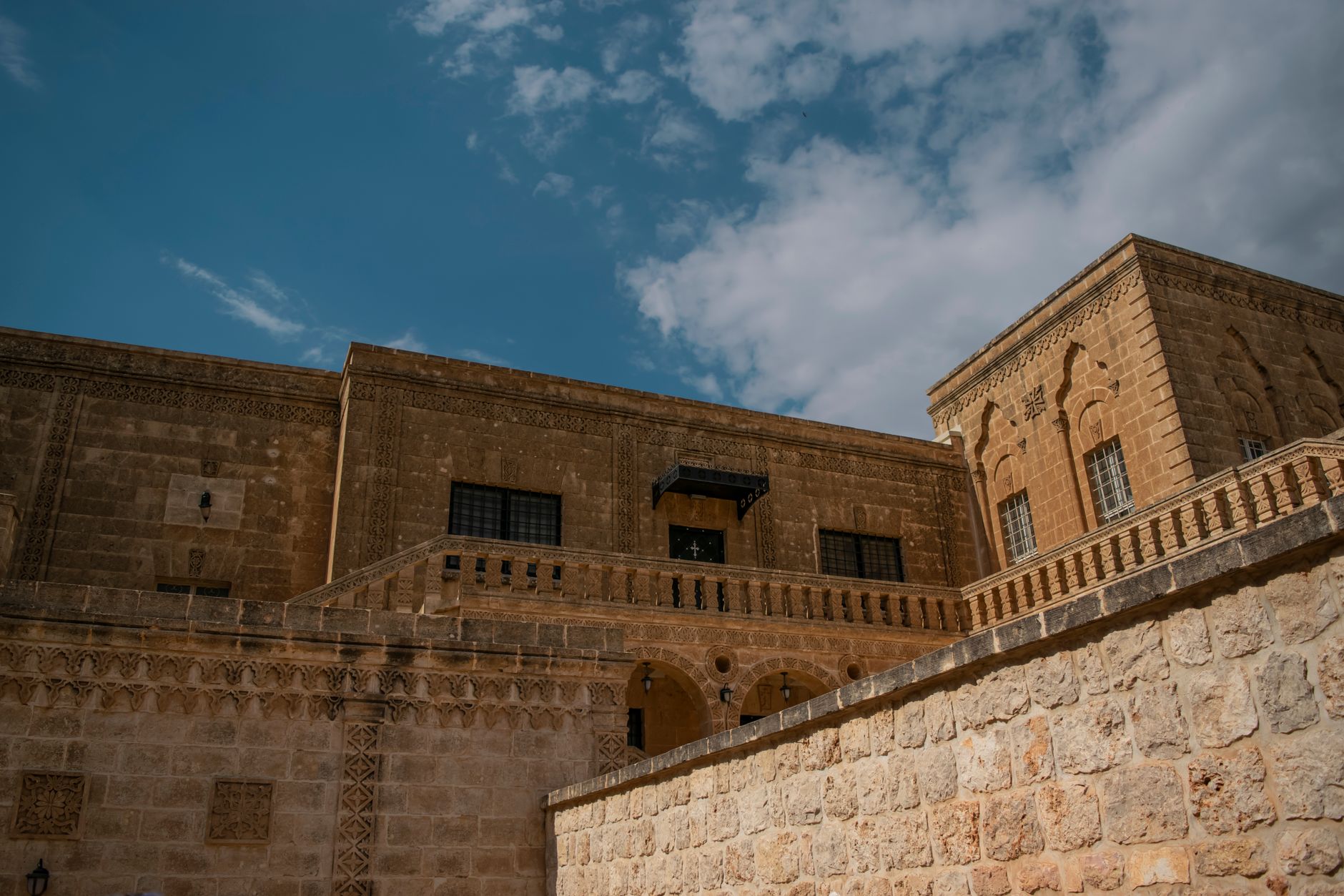 نمای استودیوی یک هنرمند در ماردین، با دیوارهای سنگی و دکوراسیون سنتی زیر آسمان آبی.