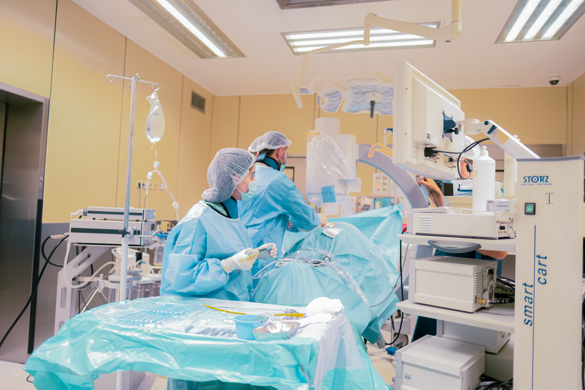 Two surgeons in scrubs working on a patient in a high-tech operating room.