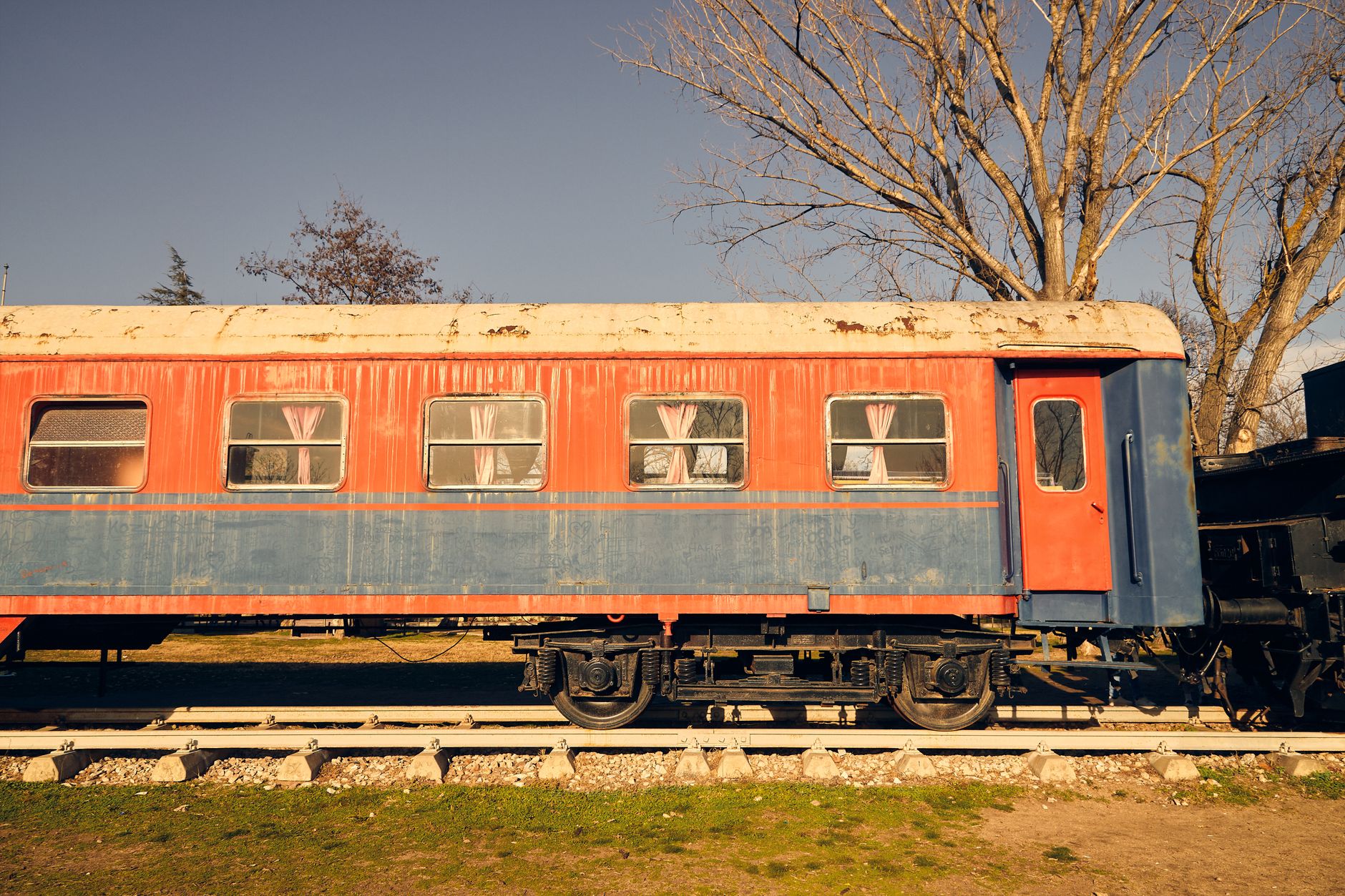 Exterior view of a colorful vintage train car in Turkey, featuring windows with curtains.