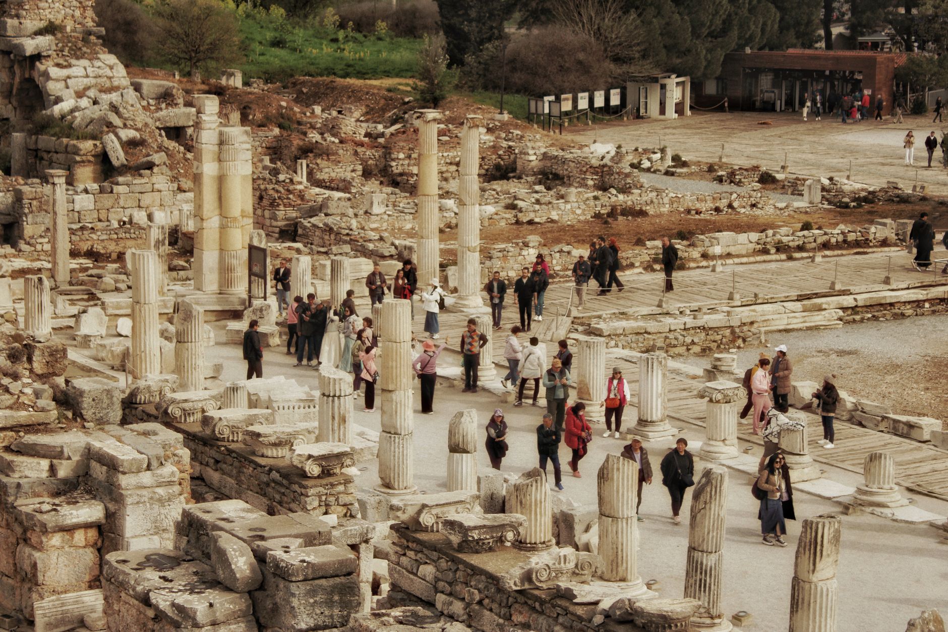 Turistler tarihi bir arkeolojik alanda antik taş sütunlar ve harabeler arasında yürüyor.