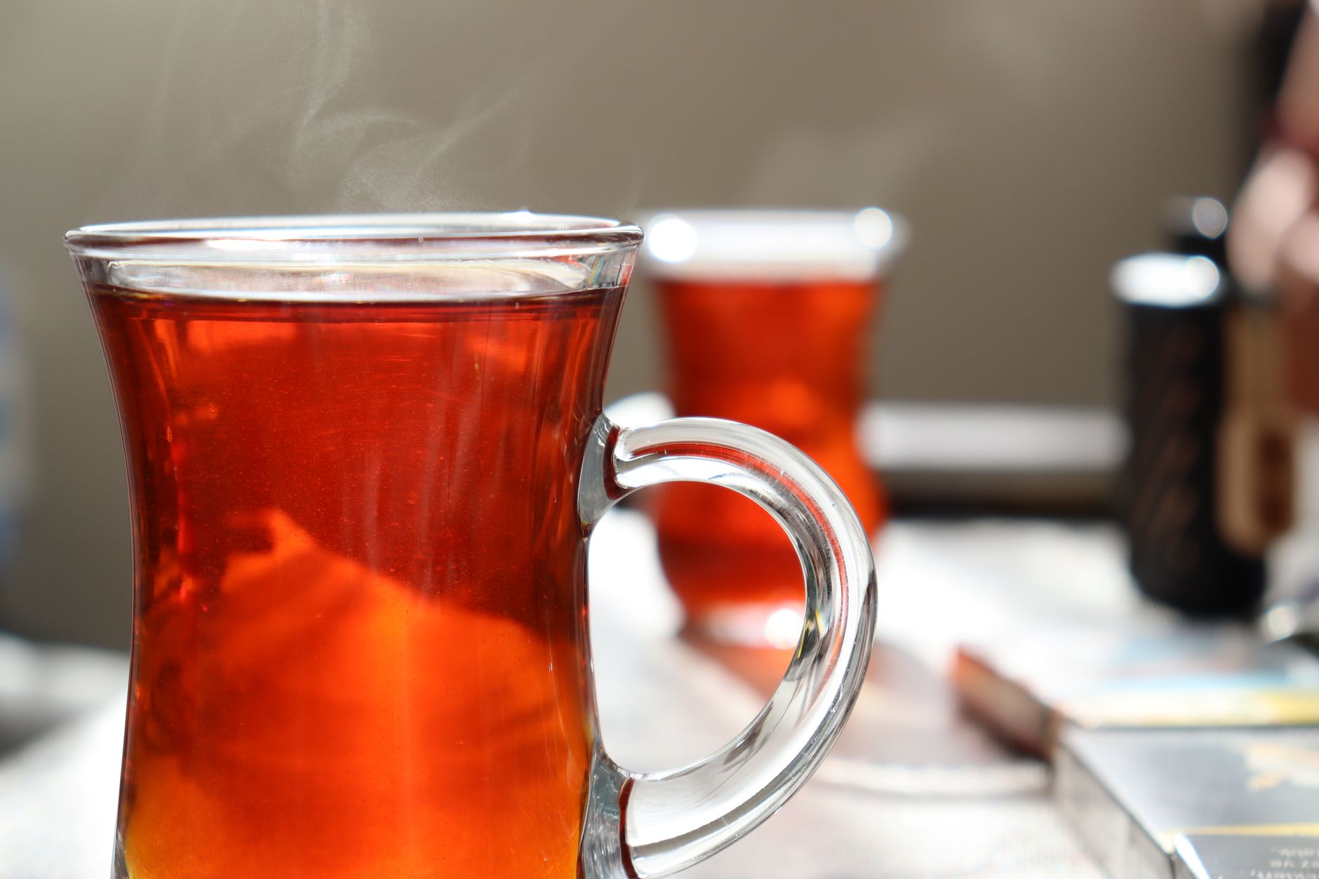 نمای نزدیک از استکان لاله‌ای پر از چای ترکی داغ در یک قهوه‌خانه.