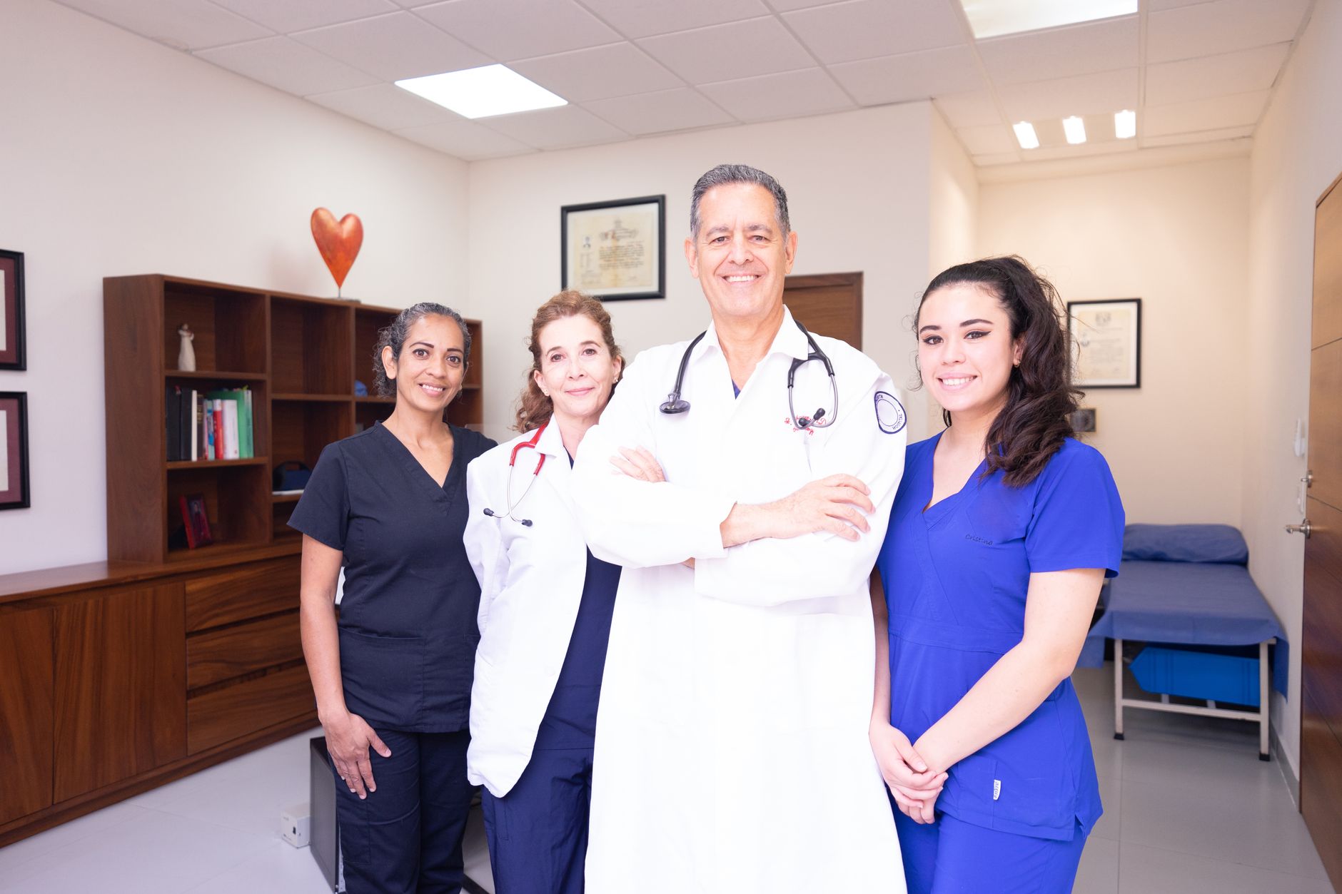 A diverse healthcare team poses together in a medical office during a post-operative follow-up consultation.