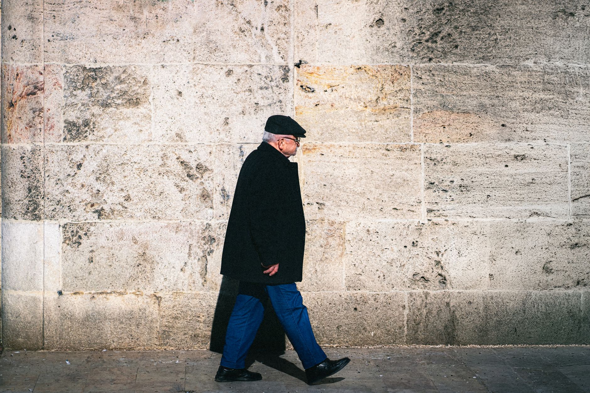 An elderly man confidently walks outdoors against a stone wall, symbolizing restored independence.