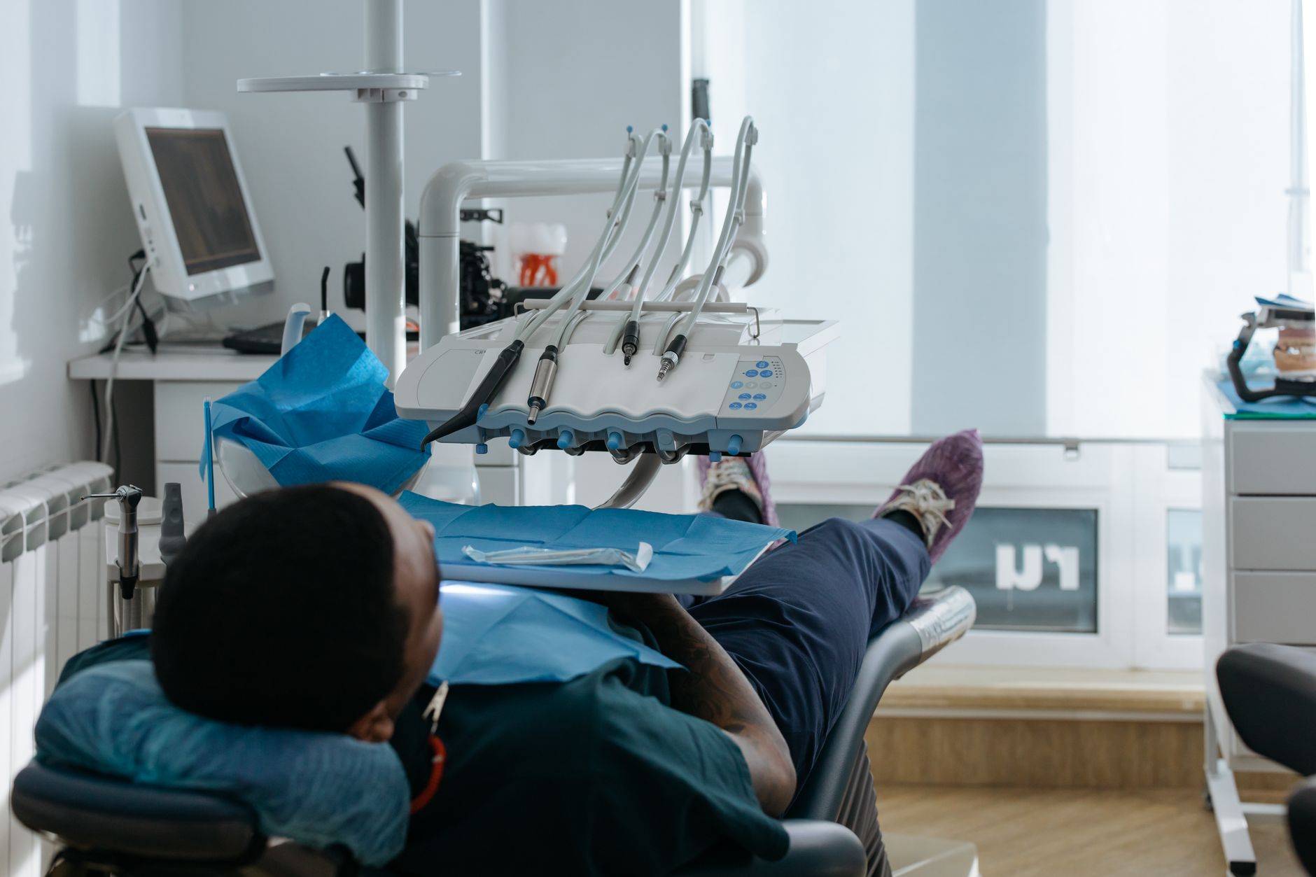 A patient lies in a dental chair wearing a sedation mask, prepared for treatment.
