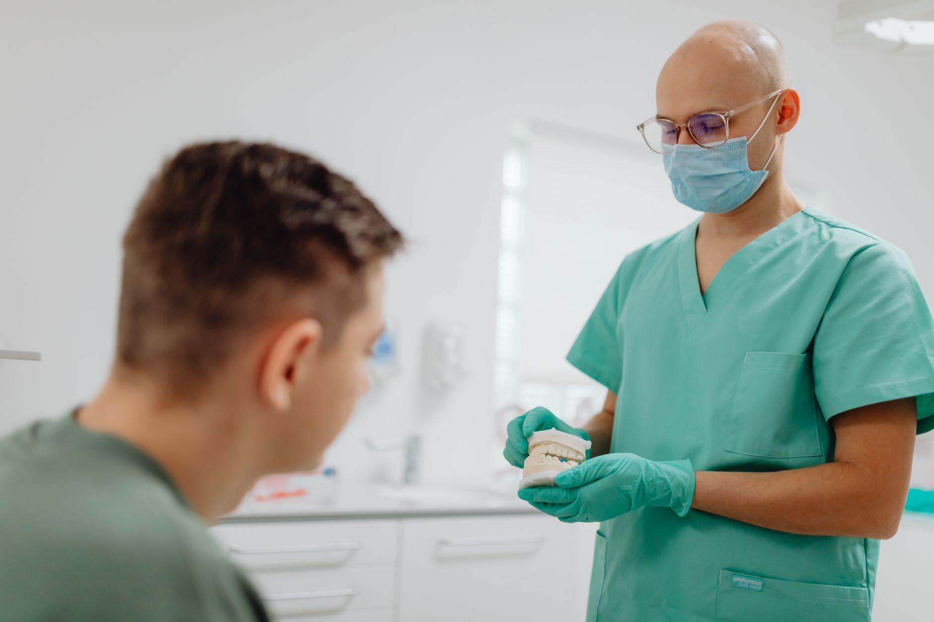 A Turkish dentist shows a dental model to an international patient in a clinic.
