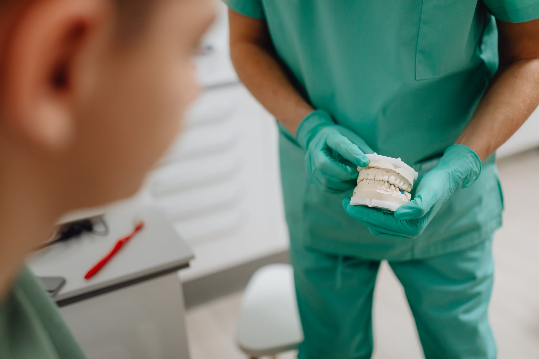 A prosthodontist shows dental model to a child at a clinic.