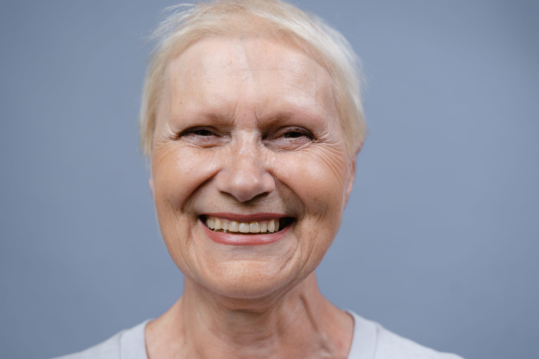 Close-up image of an older woman smiling confidently after dental restoration.