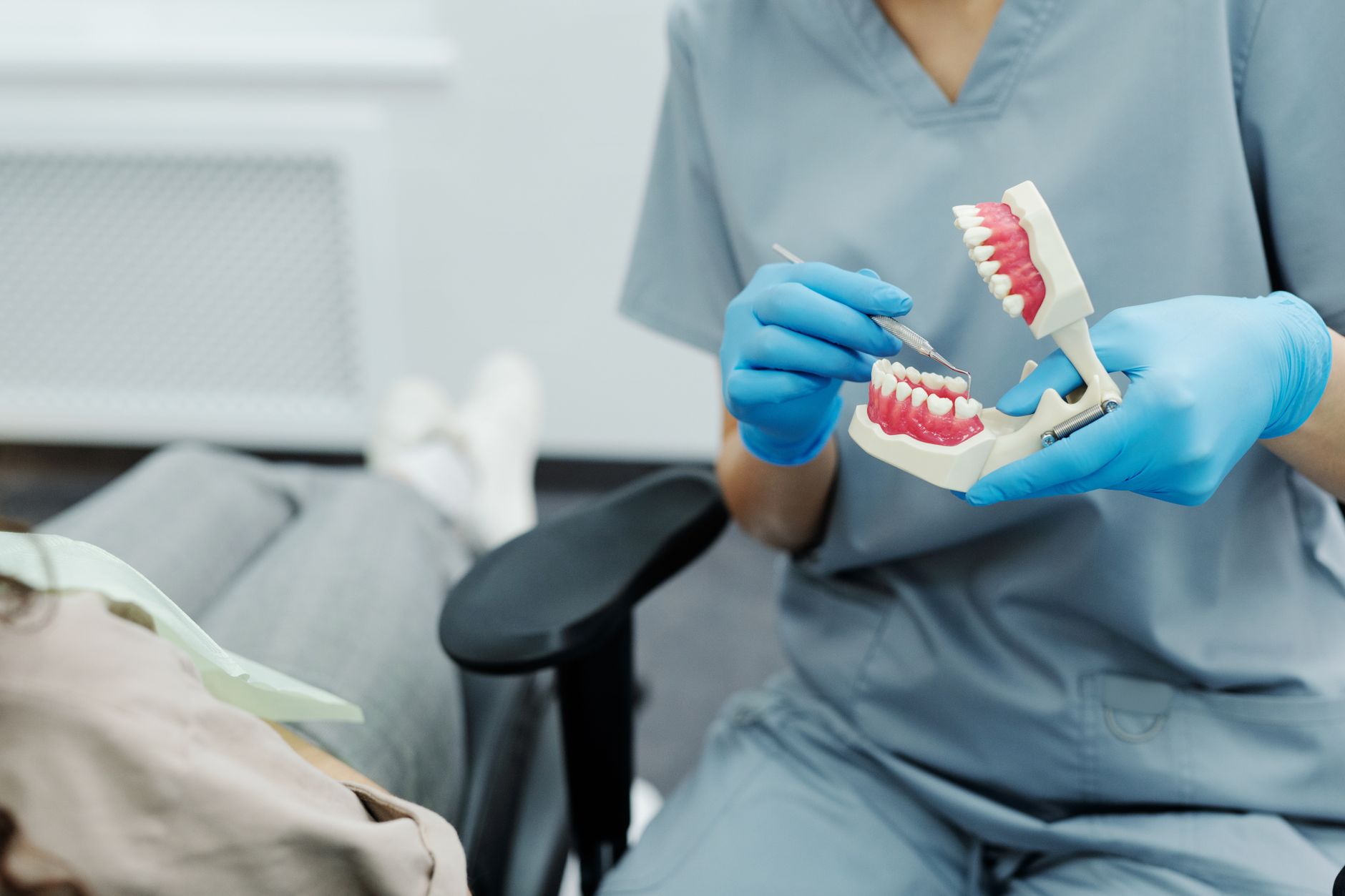 Clinician demonstrates TMJ examination using a dental model during patient consultation.